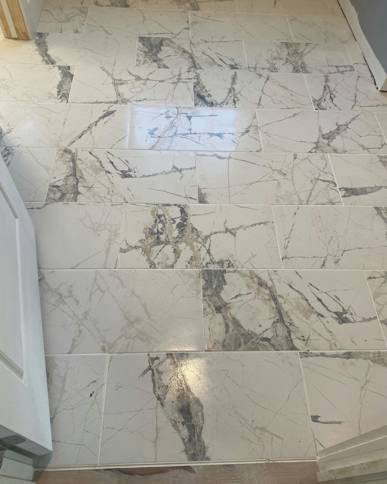 Marble-patterned tile flooring with dark gray veining. The tiles are rectangular, in a room.