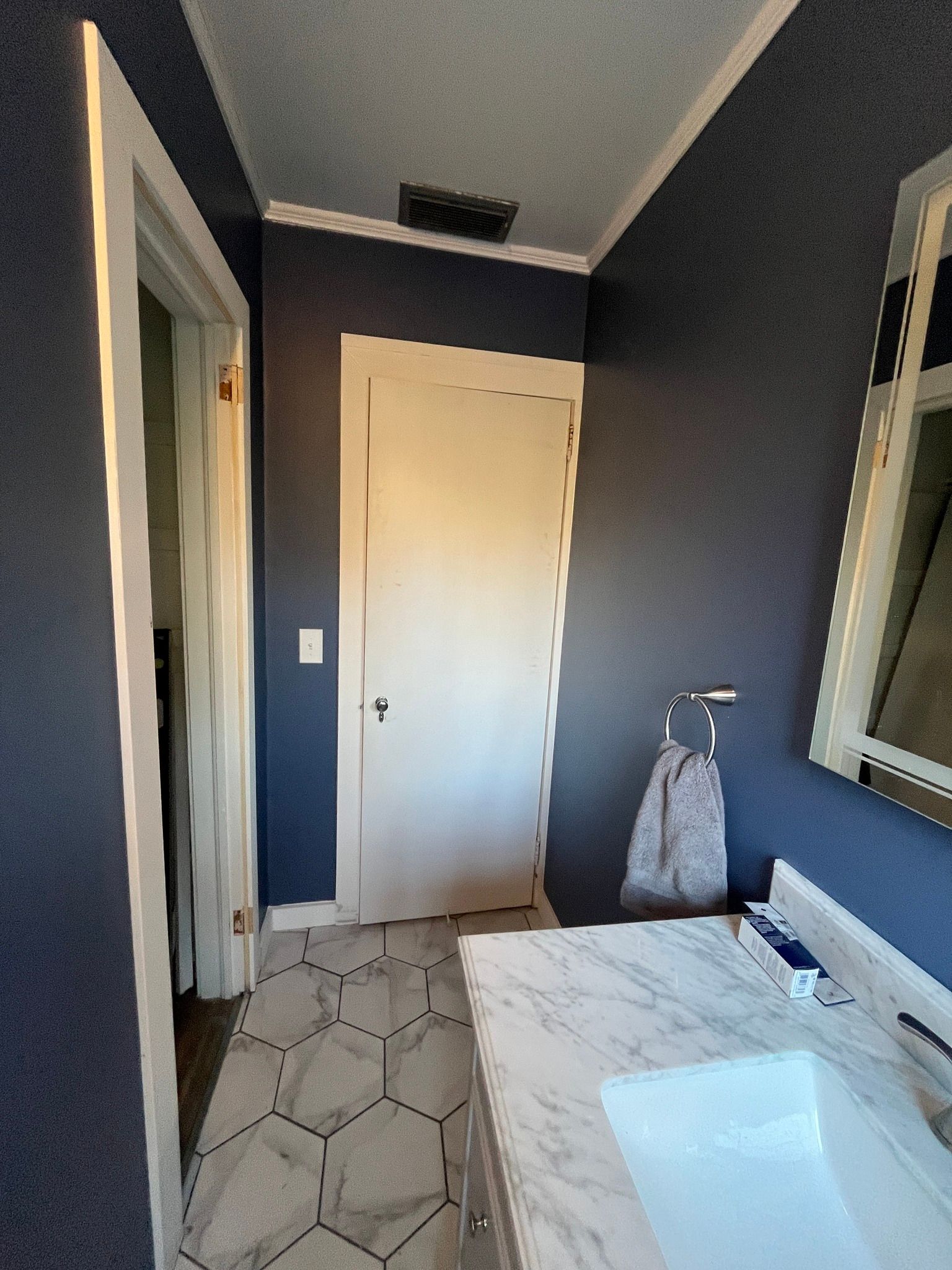 Dark blue bathroom with white trim, marble countertop, hexagon floor tiles.