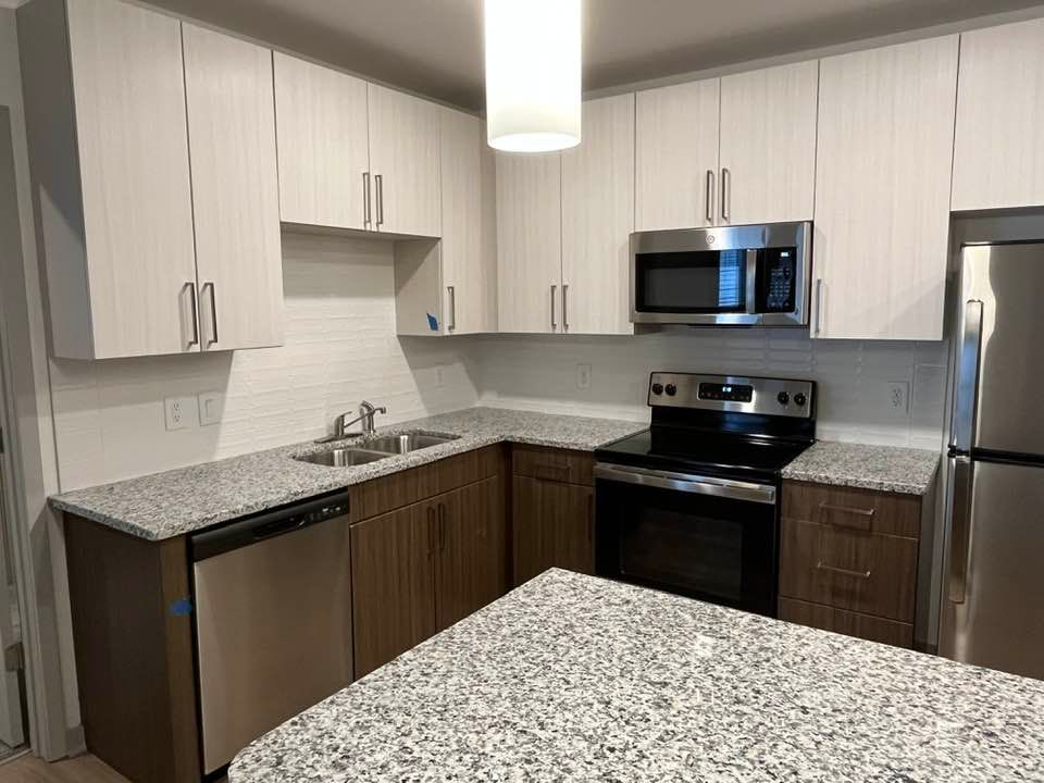 Modern kitchen with light and dark cabinets, stainless steel appliances, and granite countertops.