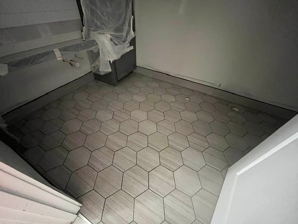 Bathroom with hexagon tile floor and partially covered vanity.