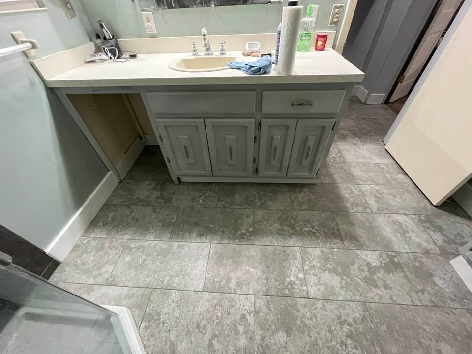 Bathroom with gray tiled floor, light blue vanity with sink and storage cabinets.