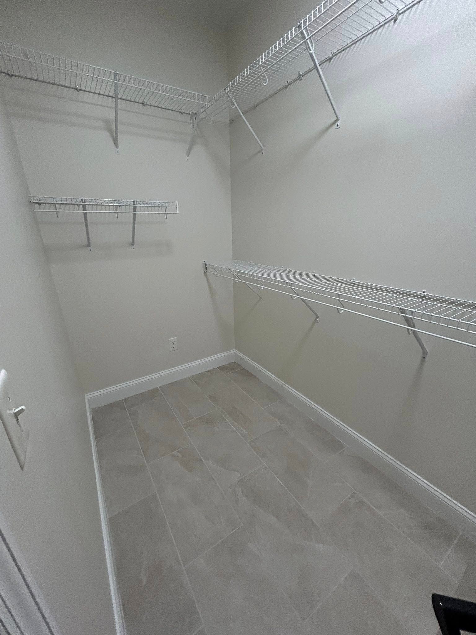 Empty walk-in closet with wire shelving and gray tile floor. White walls and trim.