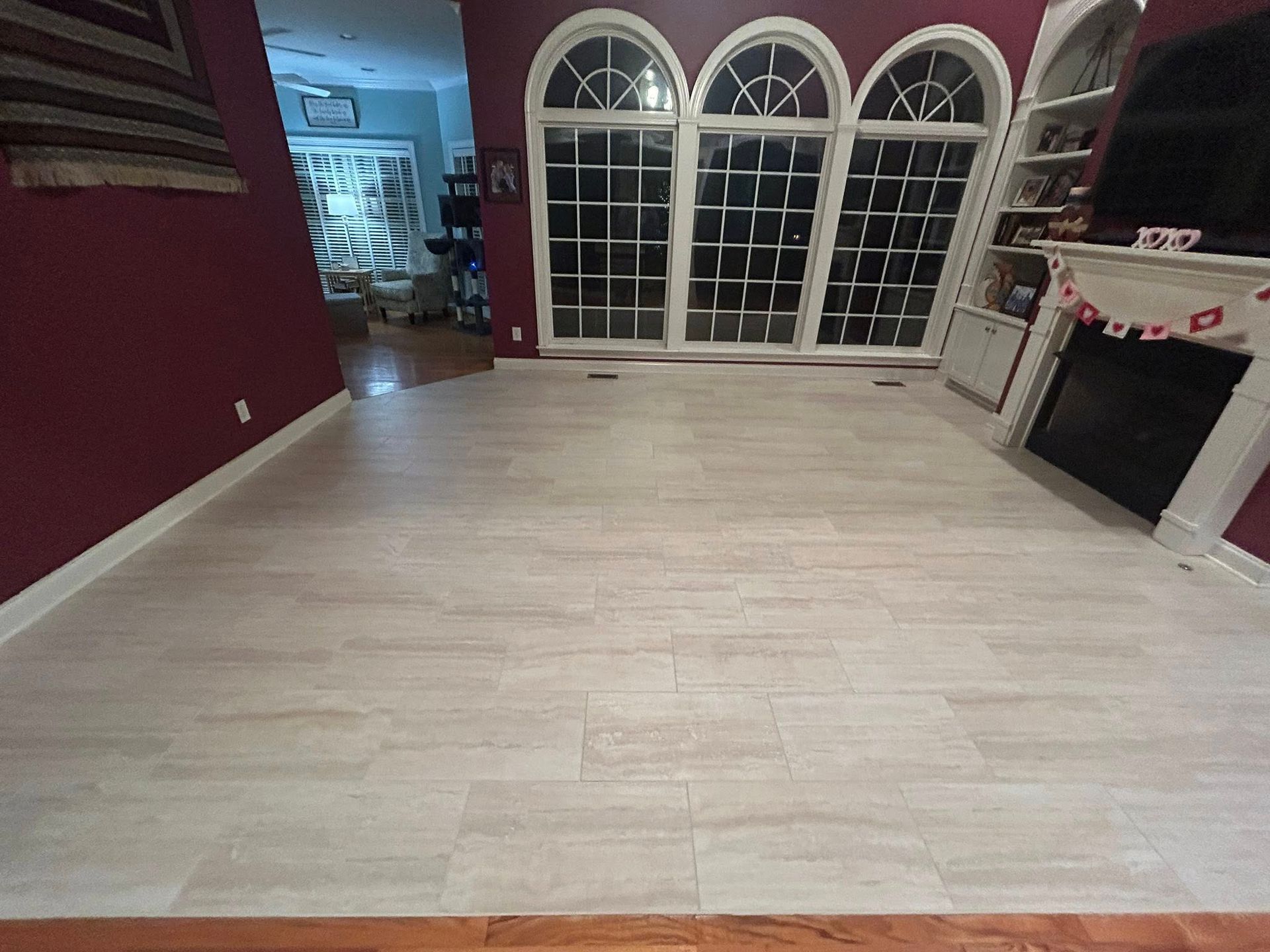 Light wood-look flooring in a living room with large windows and a fireplace.