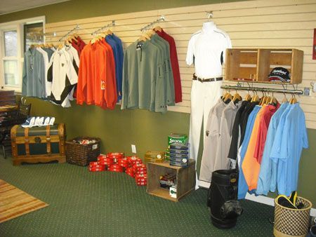 Golf apparel display in a store with shirts, jackets, and accessories on racks and shelves.