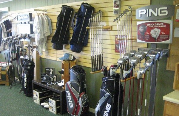 Golf equipment store: Golf clubs and bags displayed on walls and floor.
