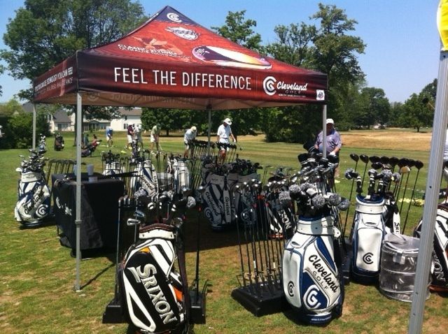 Cleveland golf equipment display at an outdoor event. Golf bags and clubs under a branded tent.