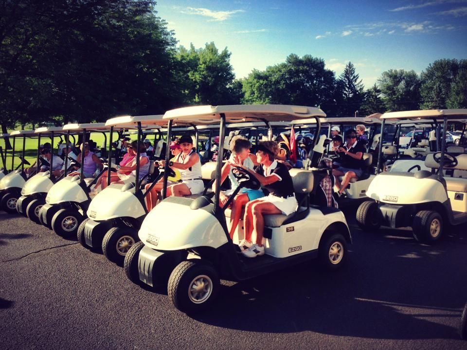 Golf carts lined up; people sitting inside, ready to play golf.