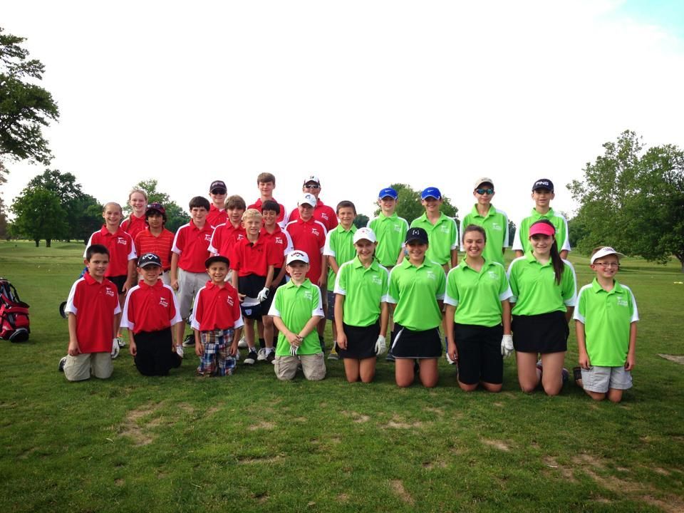 Youth golf team posing on a green, wearing red and green shirts, and hats.
