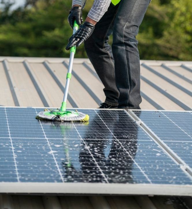 A Person is Cleaning a Solar Panel With a Mop — Exquisite Exterior Cleaning In North Gosford, NSW
