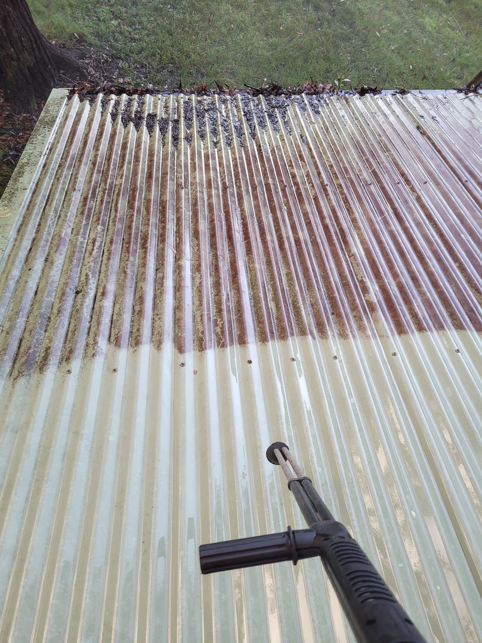 A Corrugated Metal Roof is Being Cleaned With a Pressure Washer — Exquisite Exterior Cleaning in North Gosford, NSW