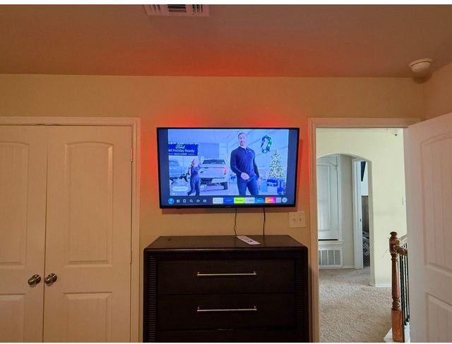 A flat-screen TV on a white wall next to a brick wall displays the Netflix home screen for the show 