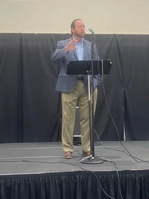 A man is standing at a podium speaking into a microphone