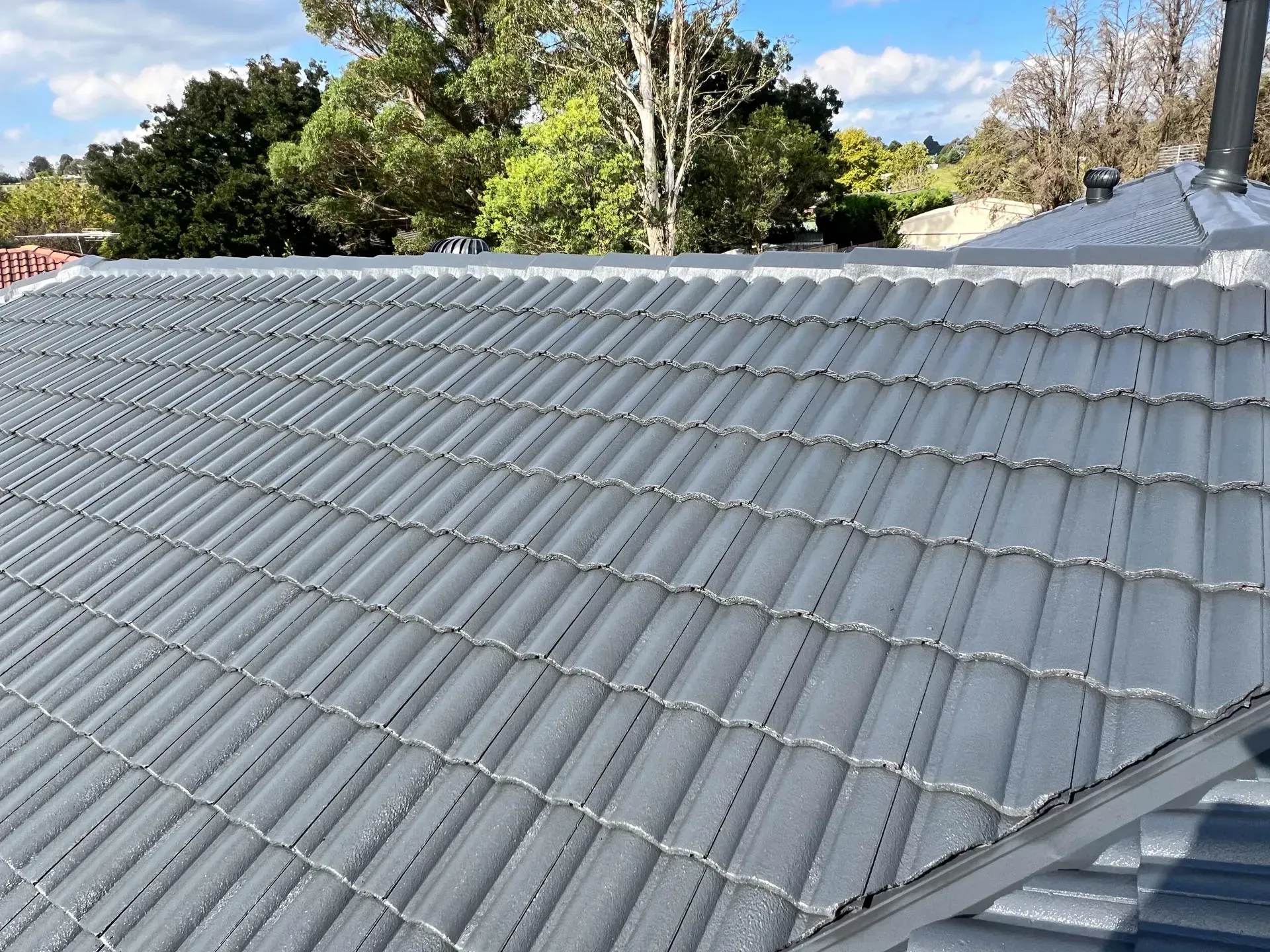 A roof with a lot of tiles on it and trees in the background