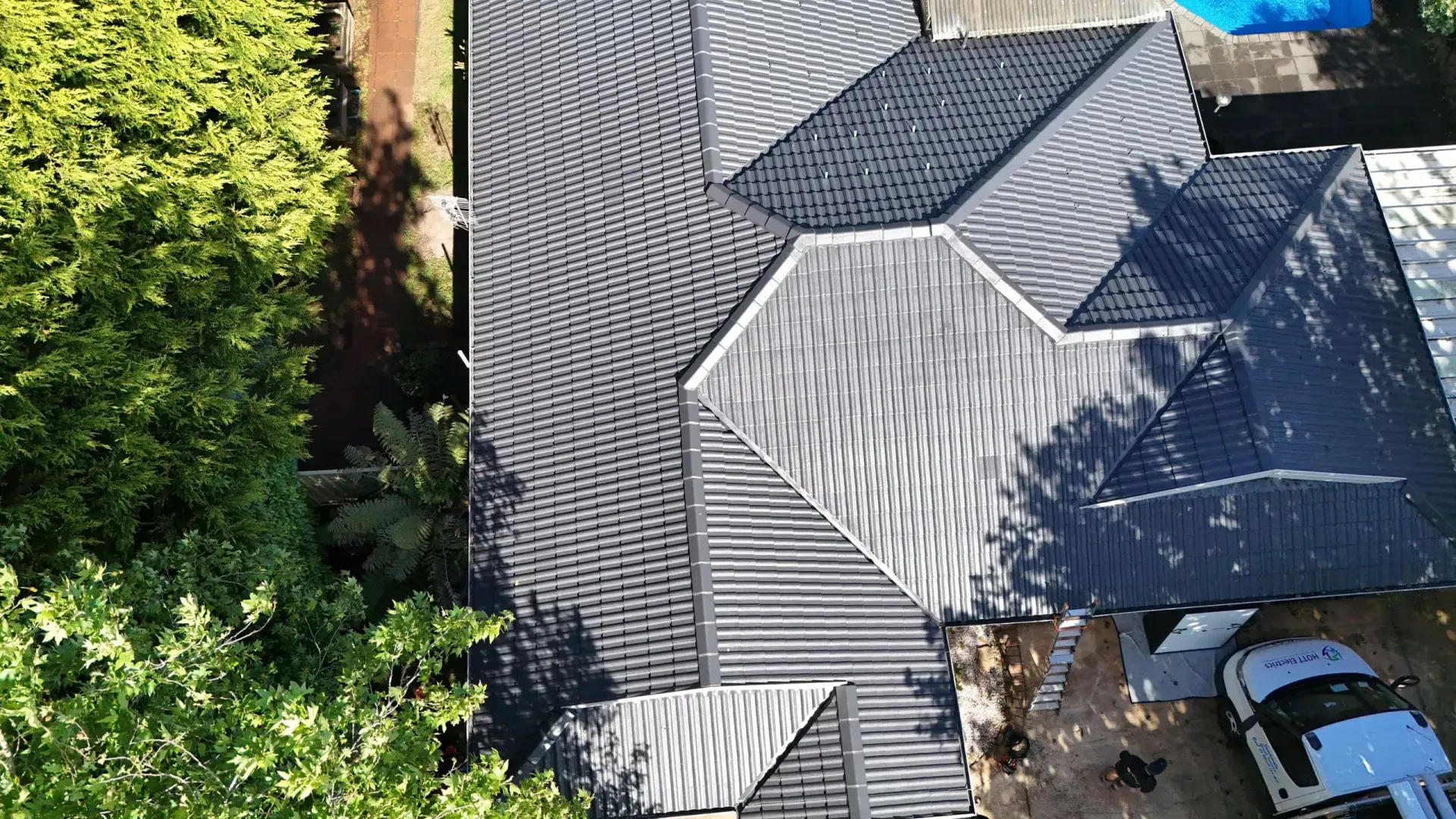 An aerial view of a house with a black roof and a white truck parked in front of it.