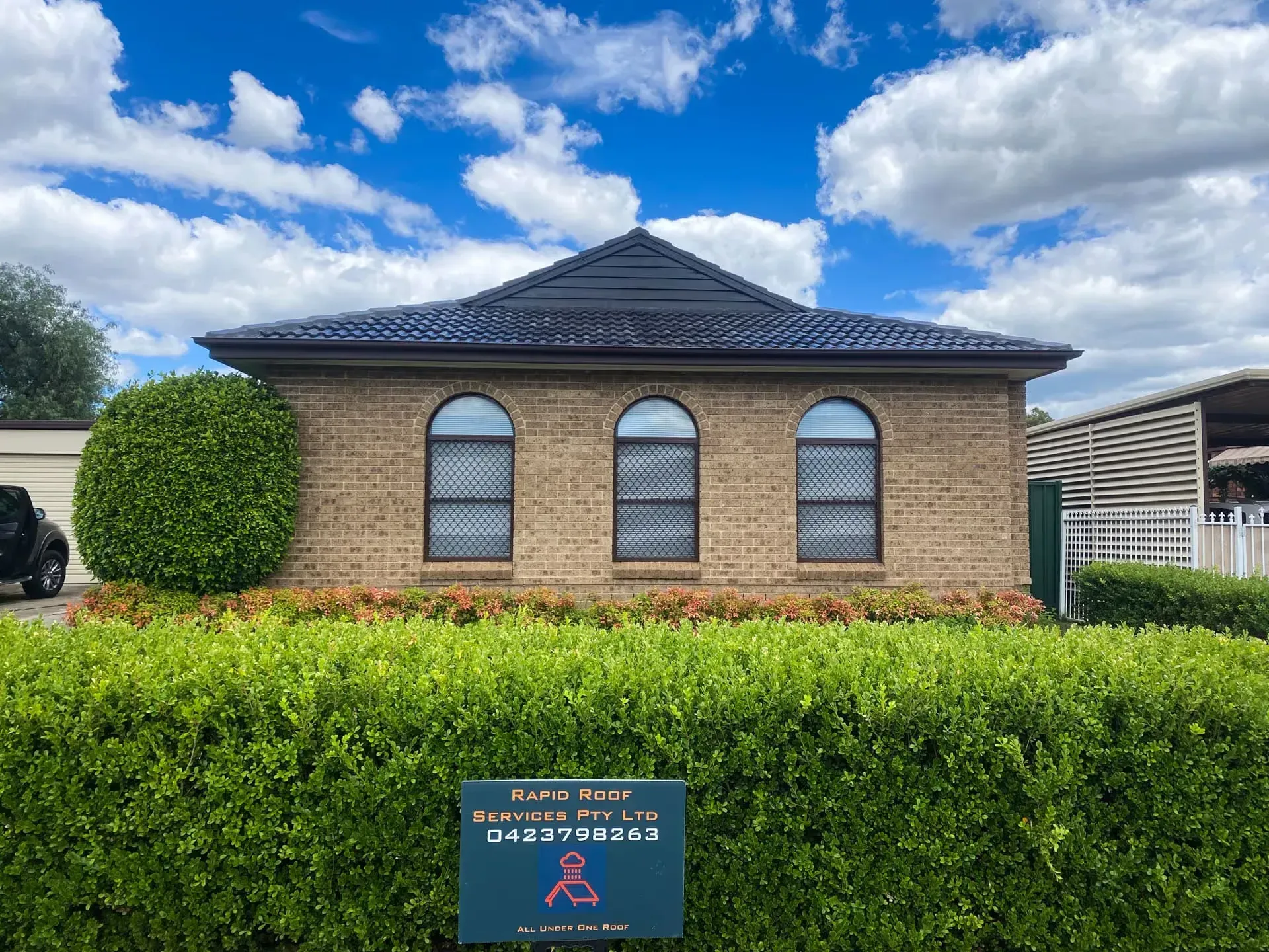 A brick house with arched windows and a sign in front of it.