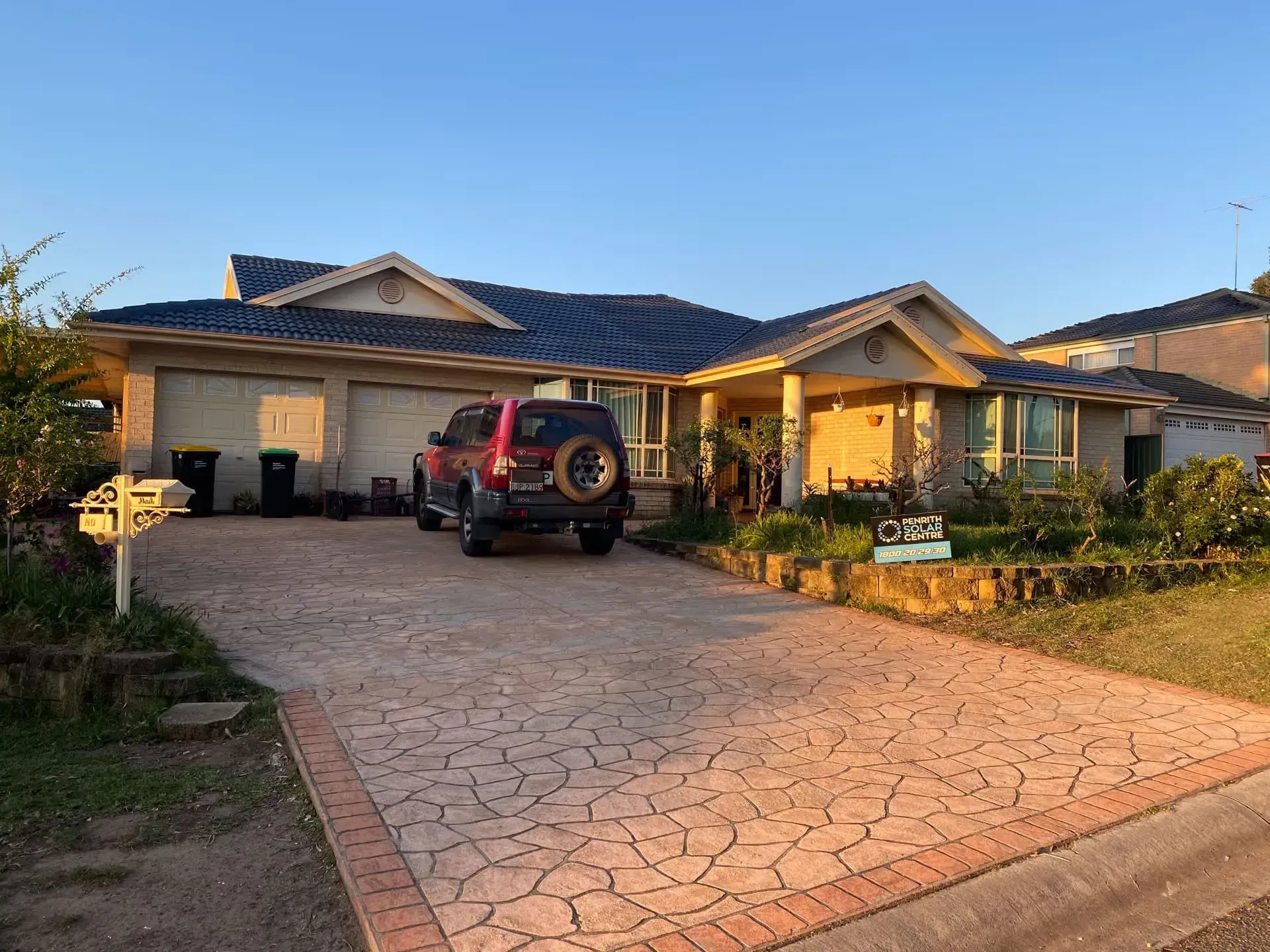 A red suv is parked in front of a large house.