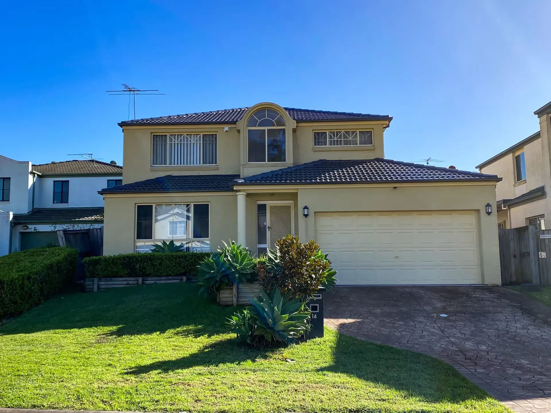 A large house with a white garage door and a lush green yard