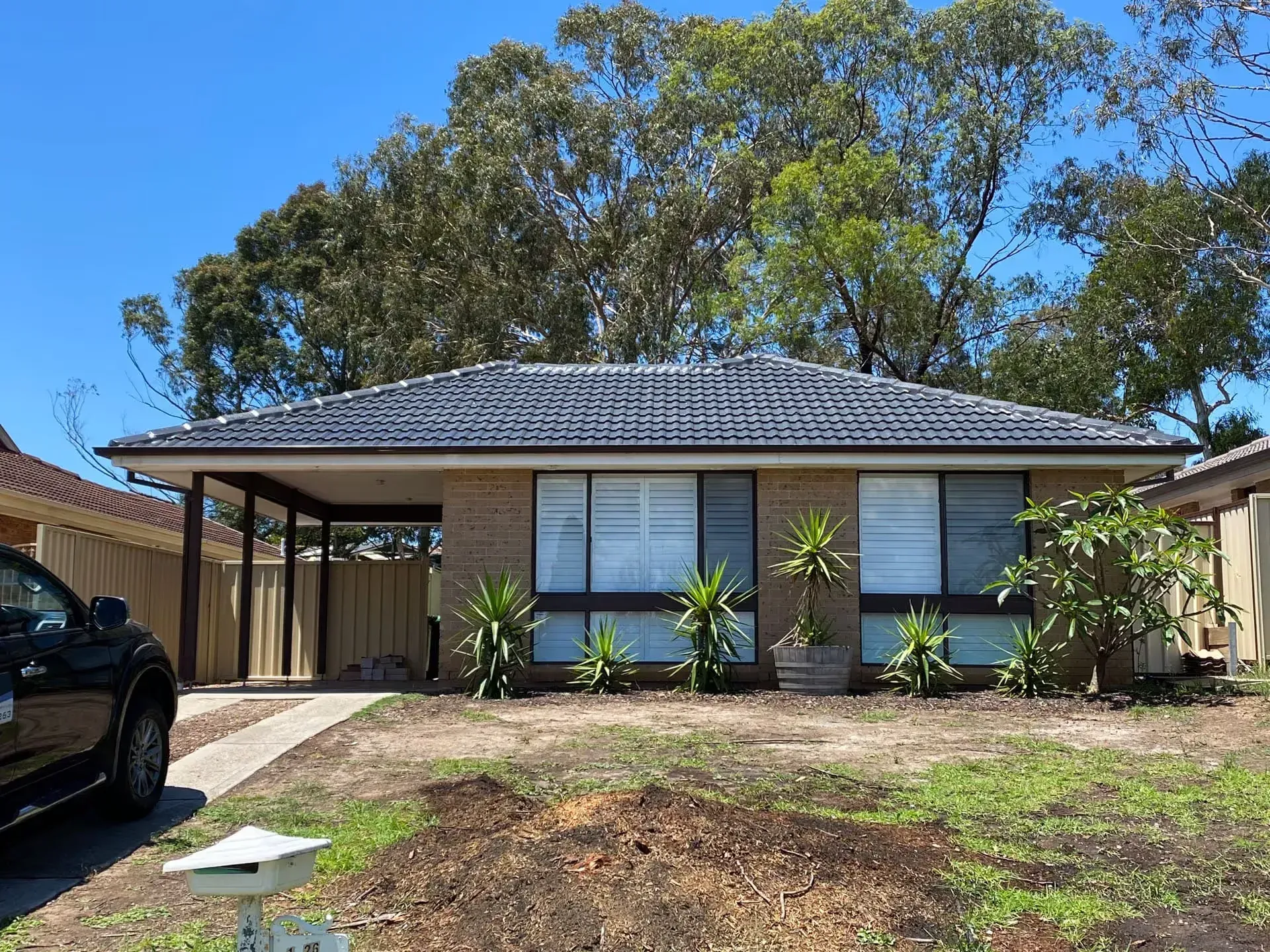 A black car is parked in front of a brick house.