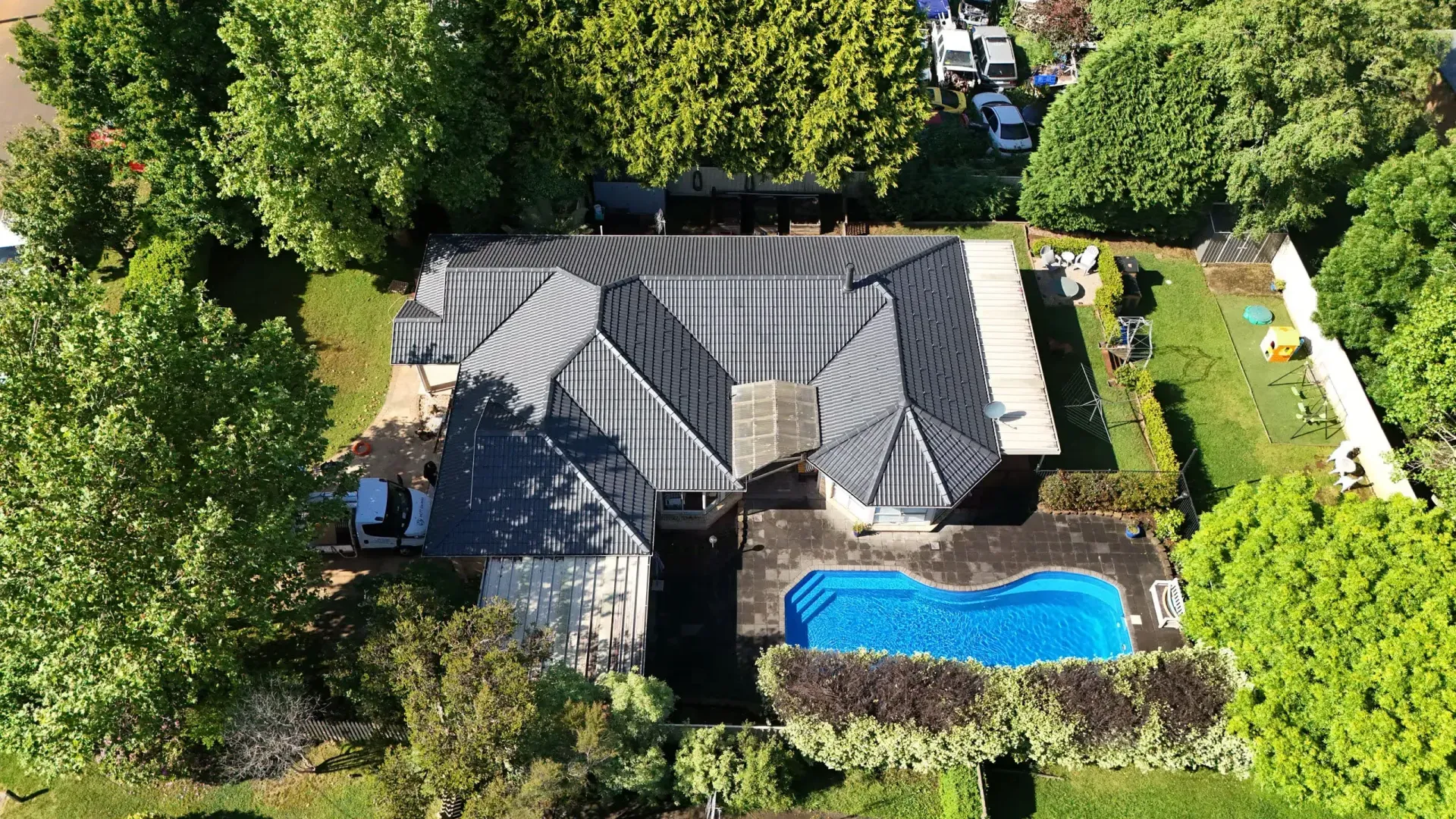 An aerial view of a house with a pool in the backyard surrounded by trees.