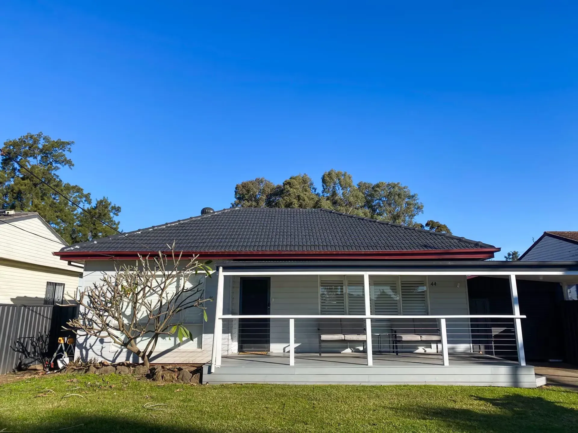 A white house with a porch and a blue sky in the background.