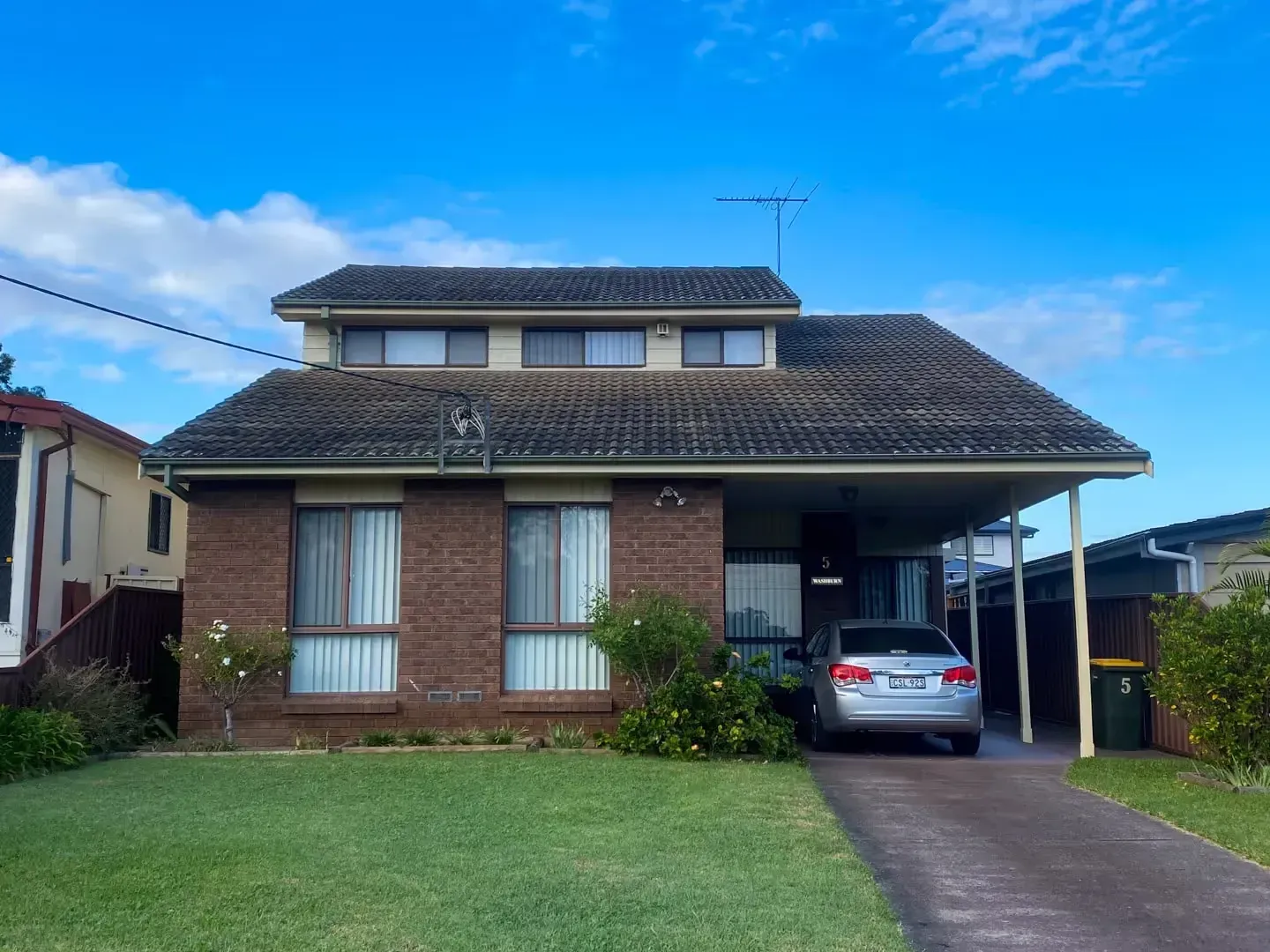A car is parked in front of a brick house