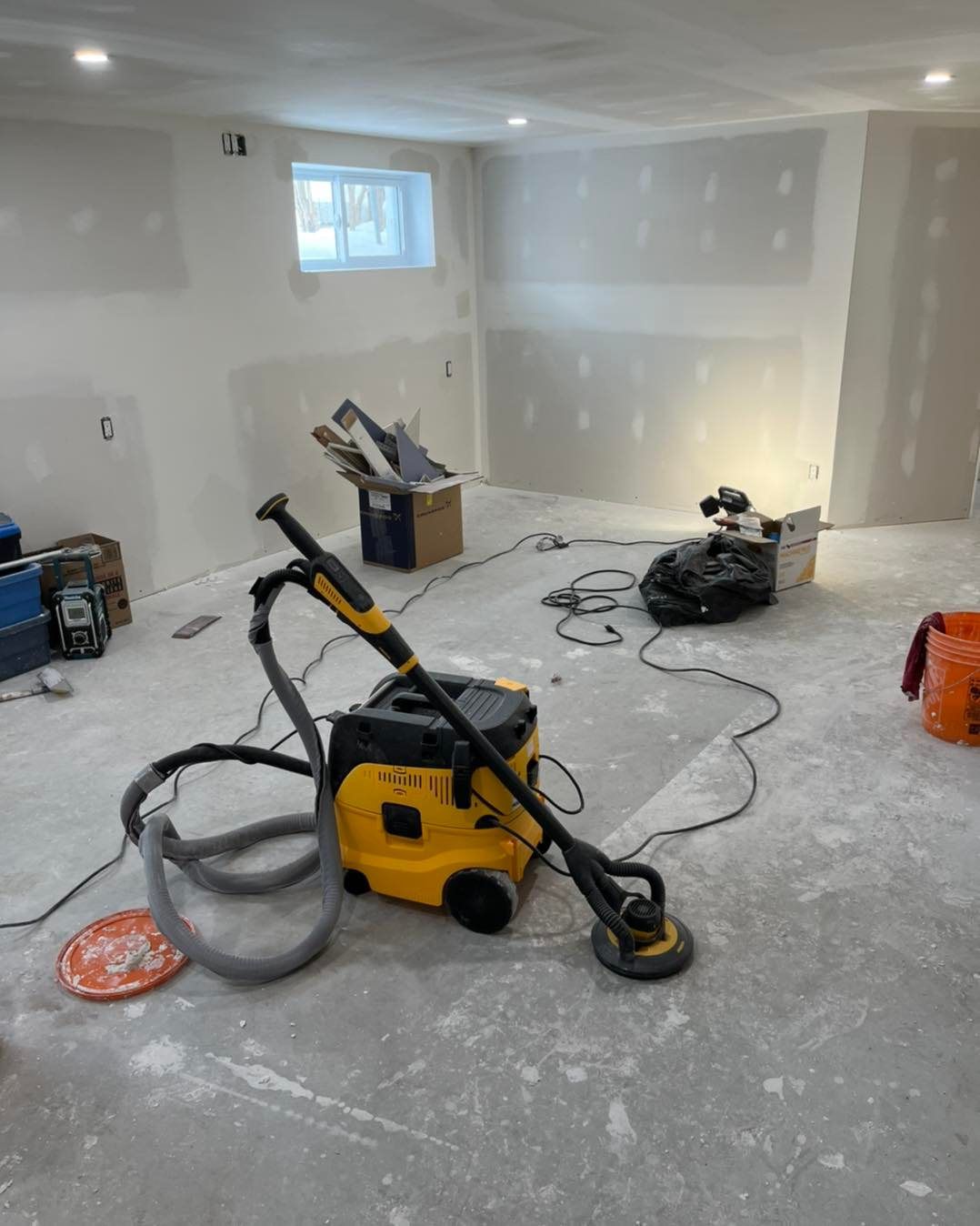 Un aspirateur est posé sur le sol d'une pièce en travaux.