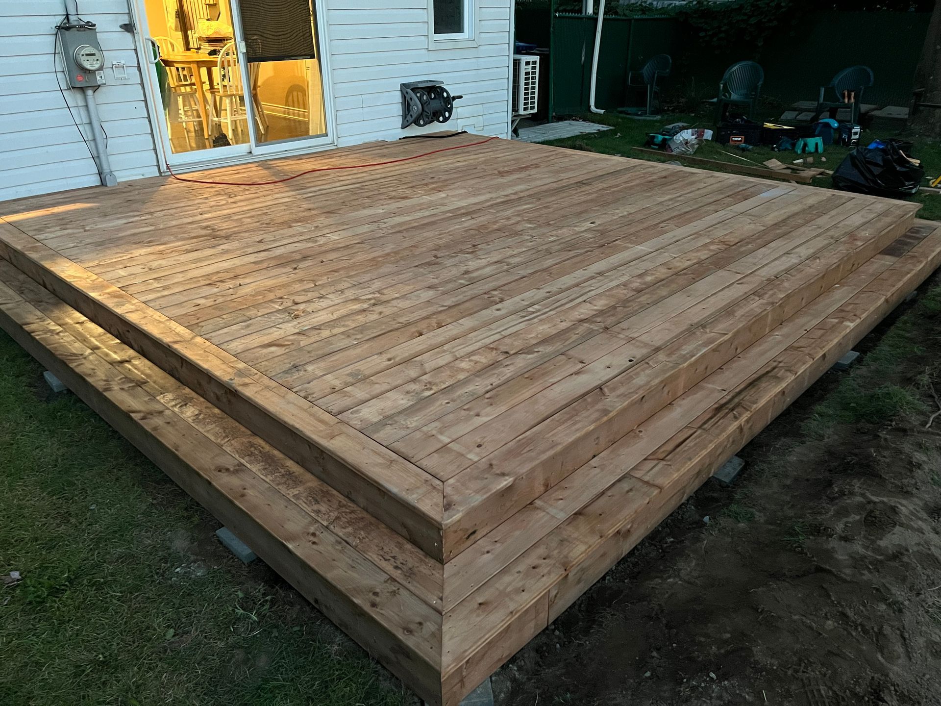 Une terrasse en bois est en cours de construction dans l'arrière-cour d'une maison.