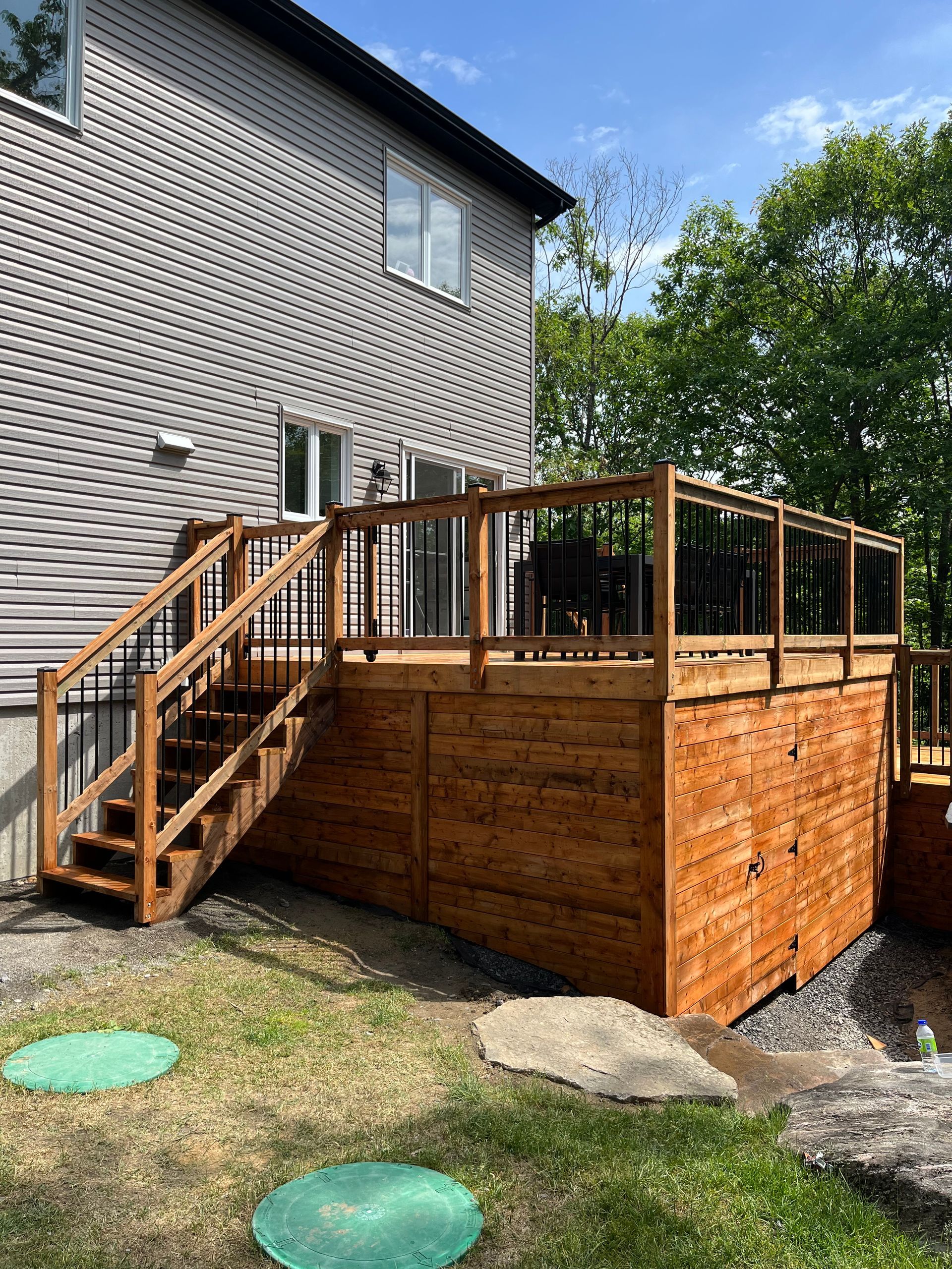 Une terrasse en bois avec des escaliers qui y mènent se trouve dans l'arrière-cour d'une maison.