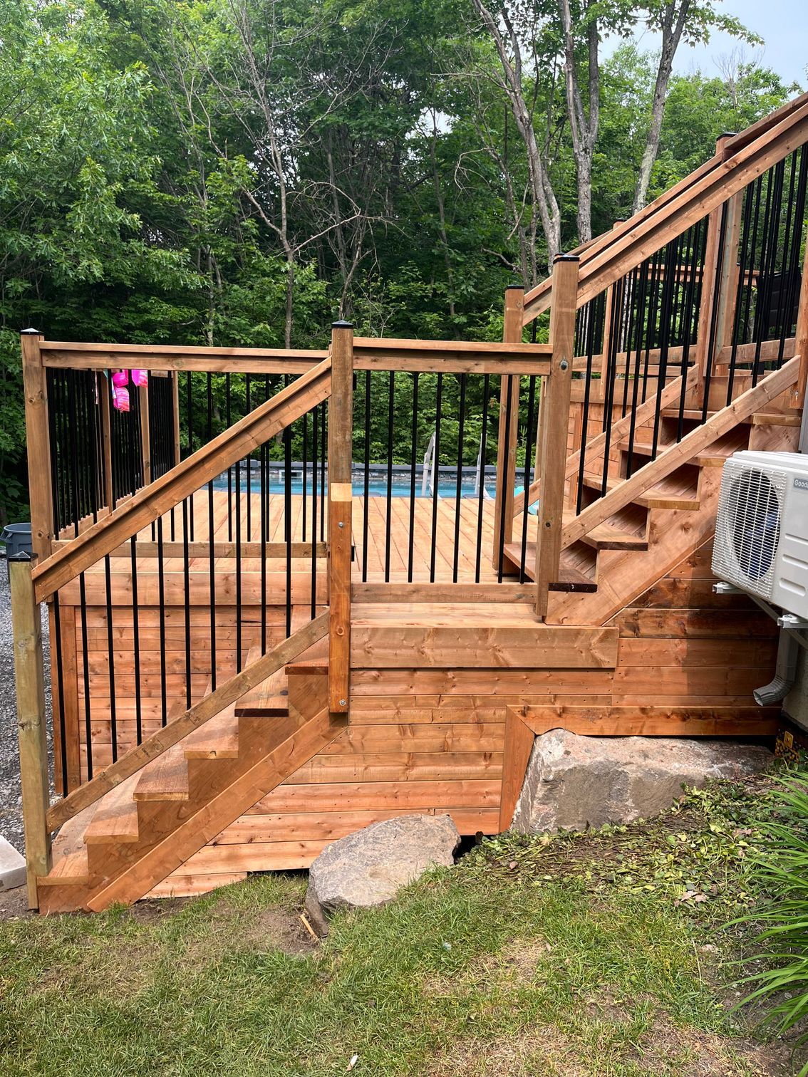 Une terrasse en bois avec des escaliers menant à une piscine.