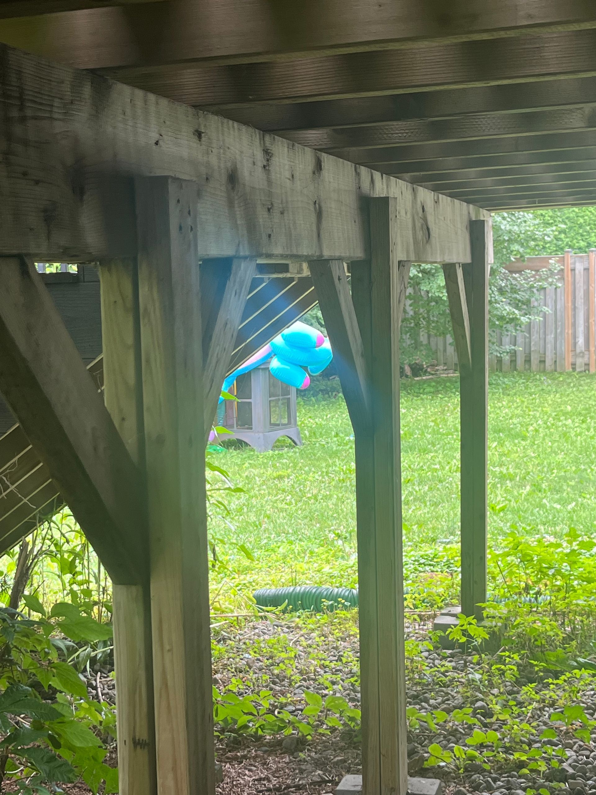 Un ballon bleu flotte dans l'herbe sous une terrasse en bois.