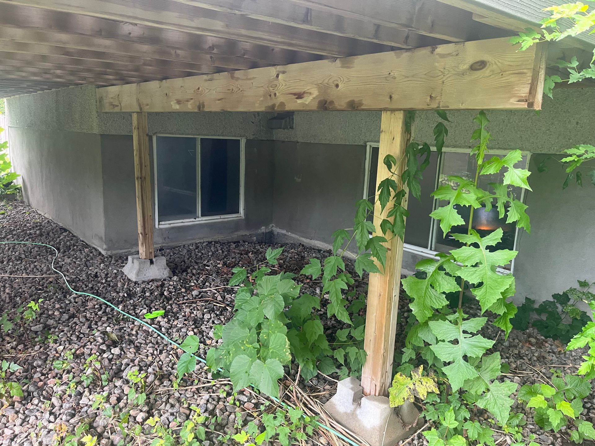 Une pergola en bois est placée sous une maison à côté d'une fenêtre.