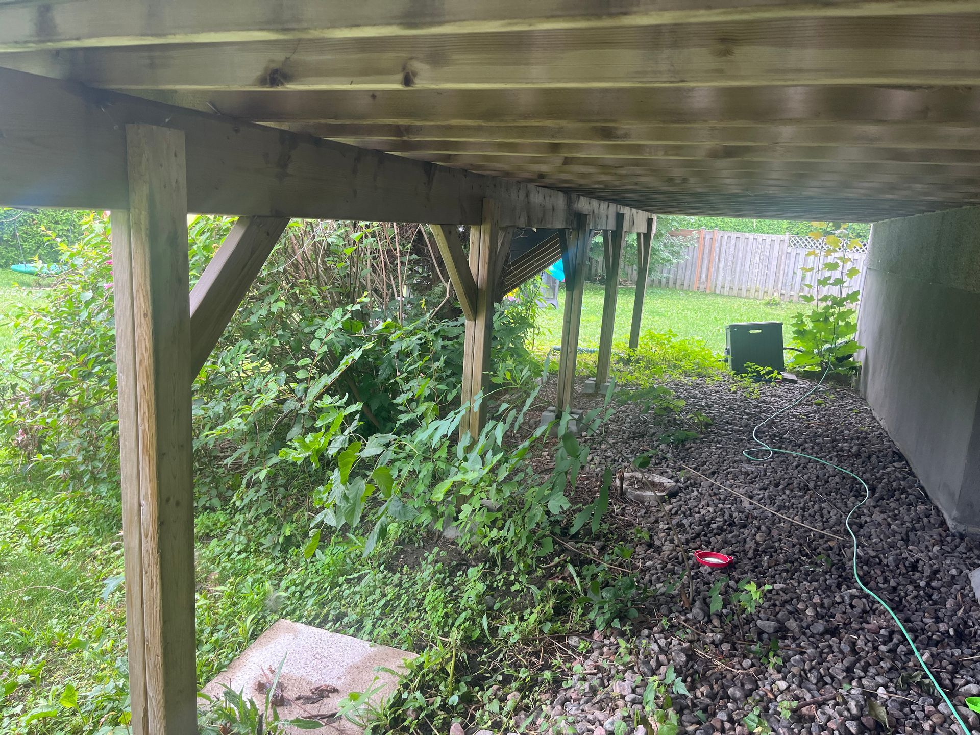 Le dessous d'une terrasse en bois avec un tuyau attaché dessus.