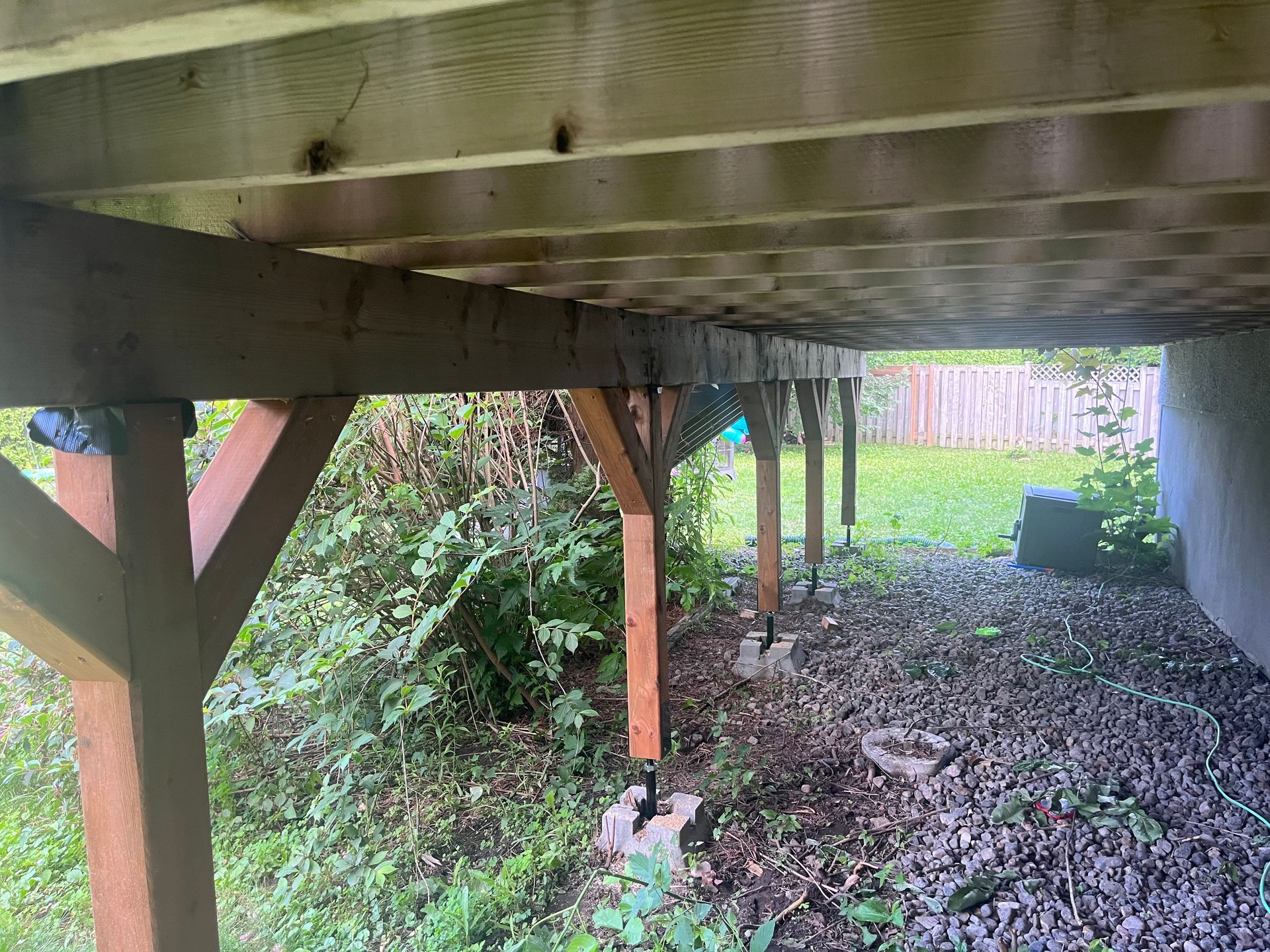 Le dessous d'une terrasse en bois avec une clôture en arrière-plan.