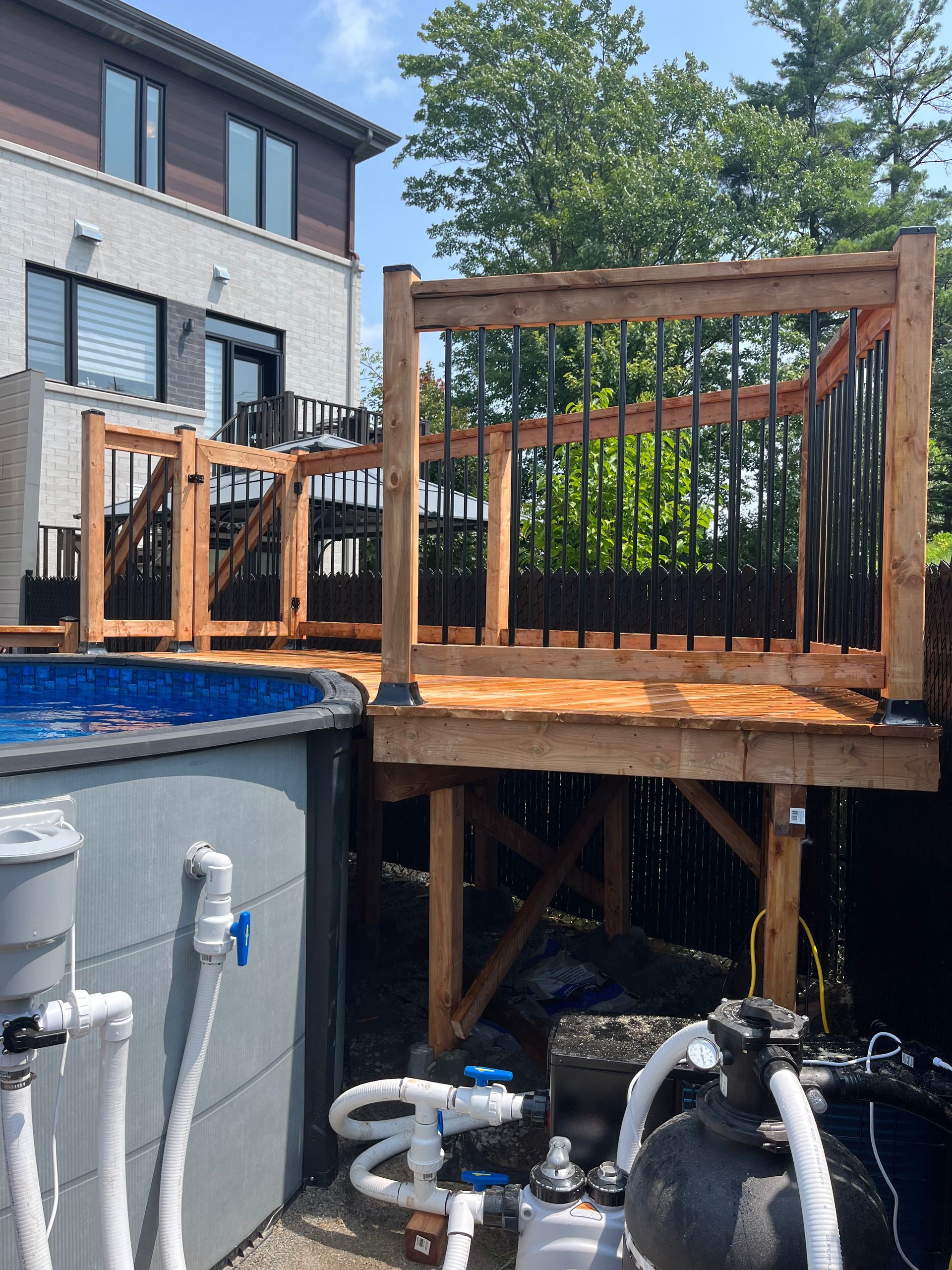 Une terrasse en bois au-dessus d'une piscine avec une maison en arrière-plan