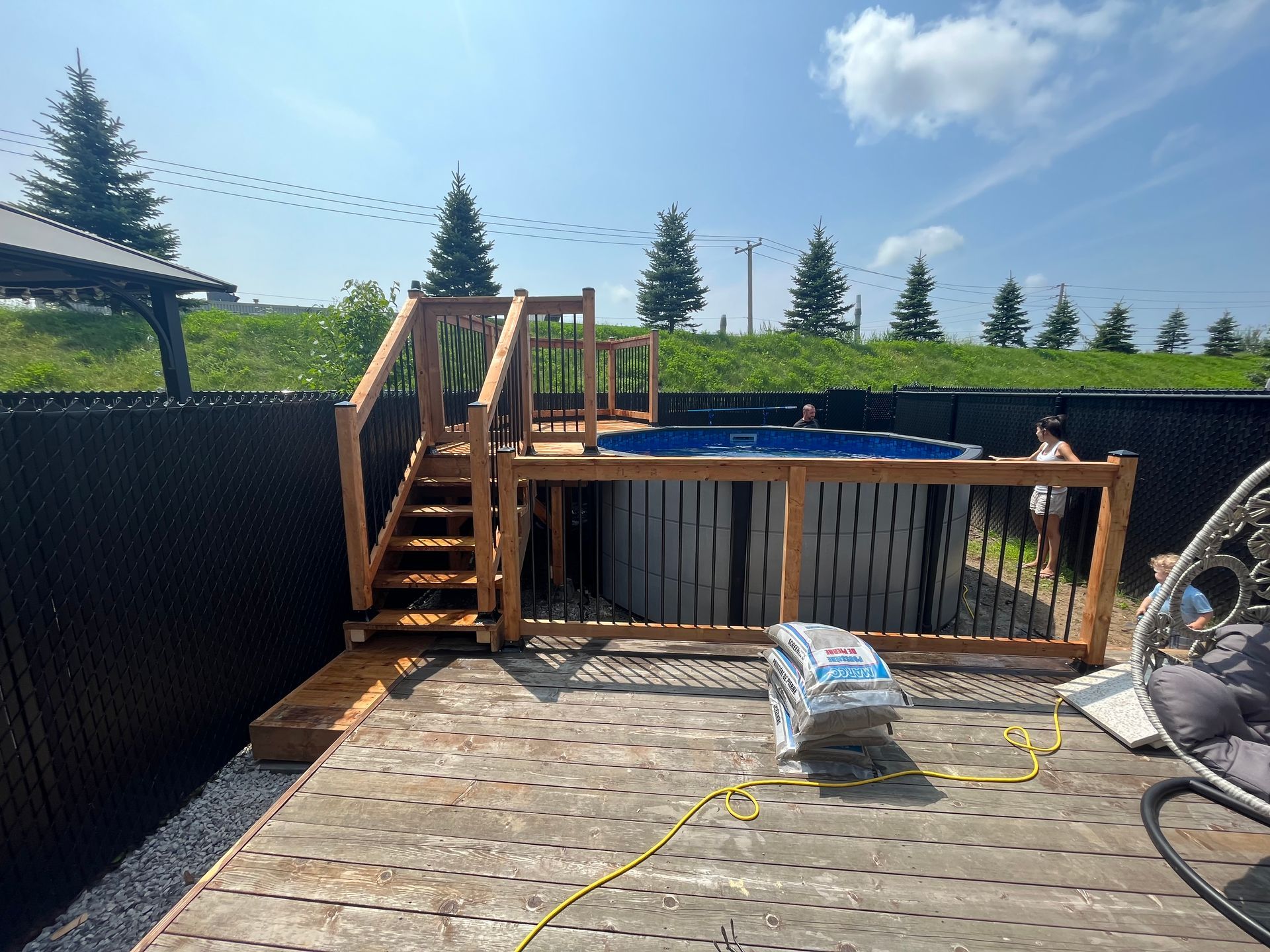 Une terrasse en bois avec des escaliers menant à une piscine.
