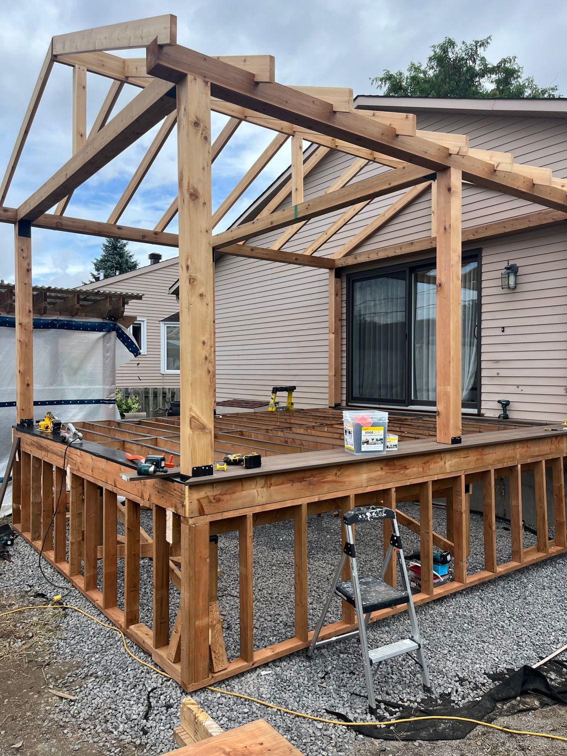 Une terrasse en bois est en cours de construction devant une maison.