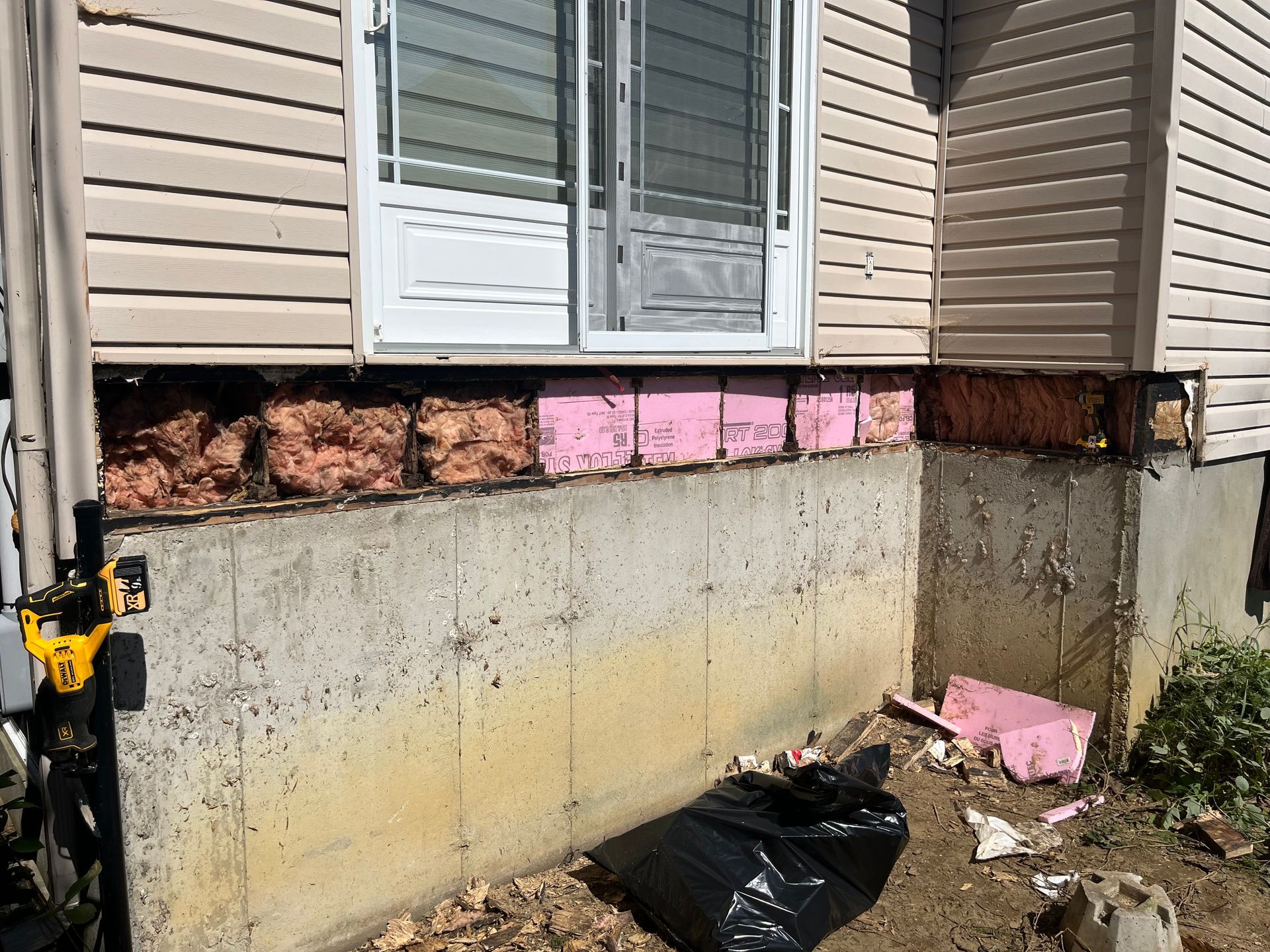 Une maison avec une fenêtre et une fondation en béton est en cours de rénovation.