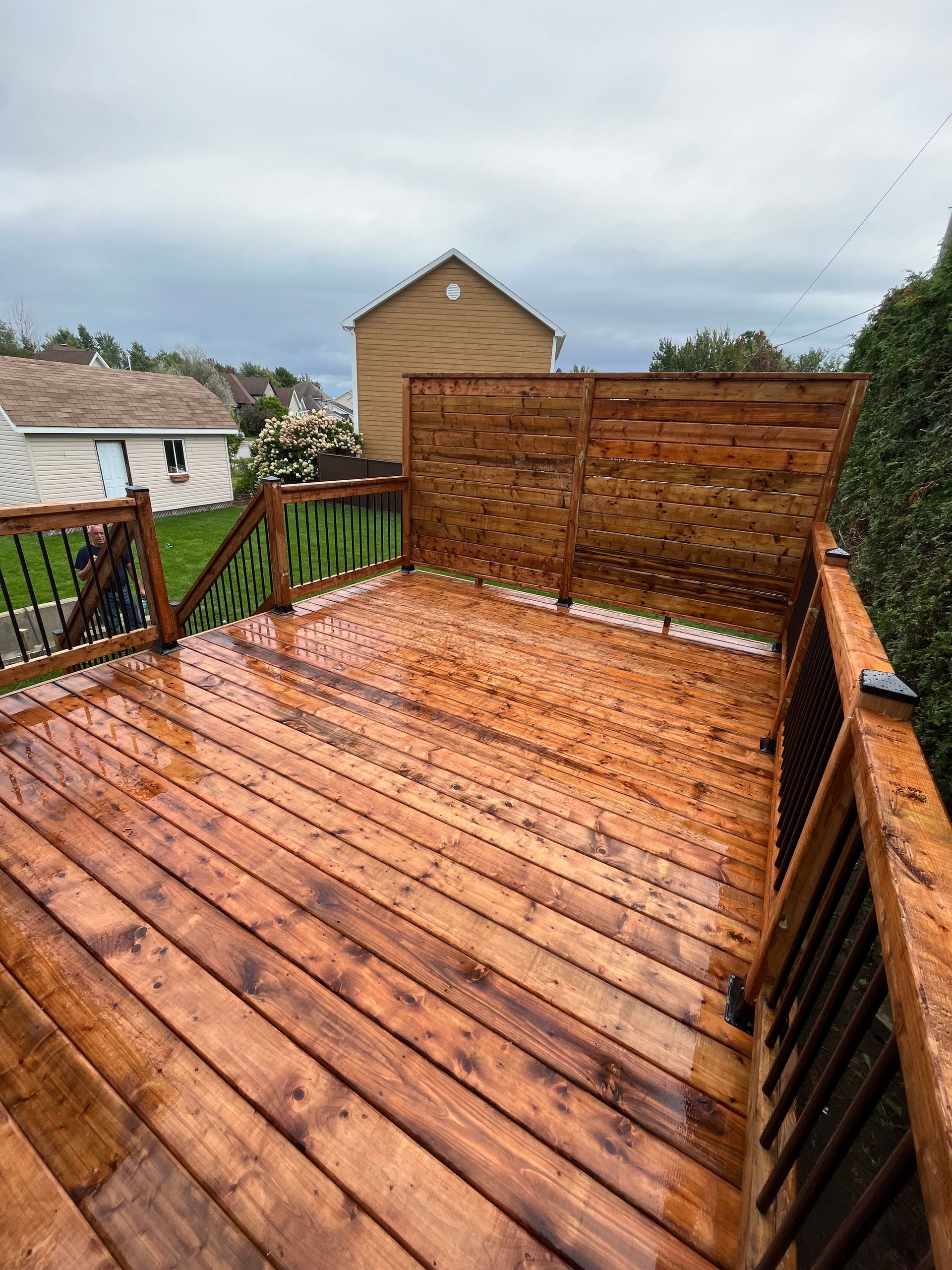 Une terrasse en bois avec une balustrade et une maison en arrière-plan.