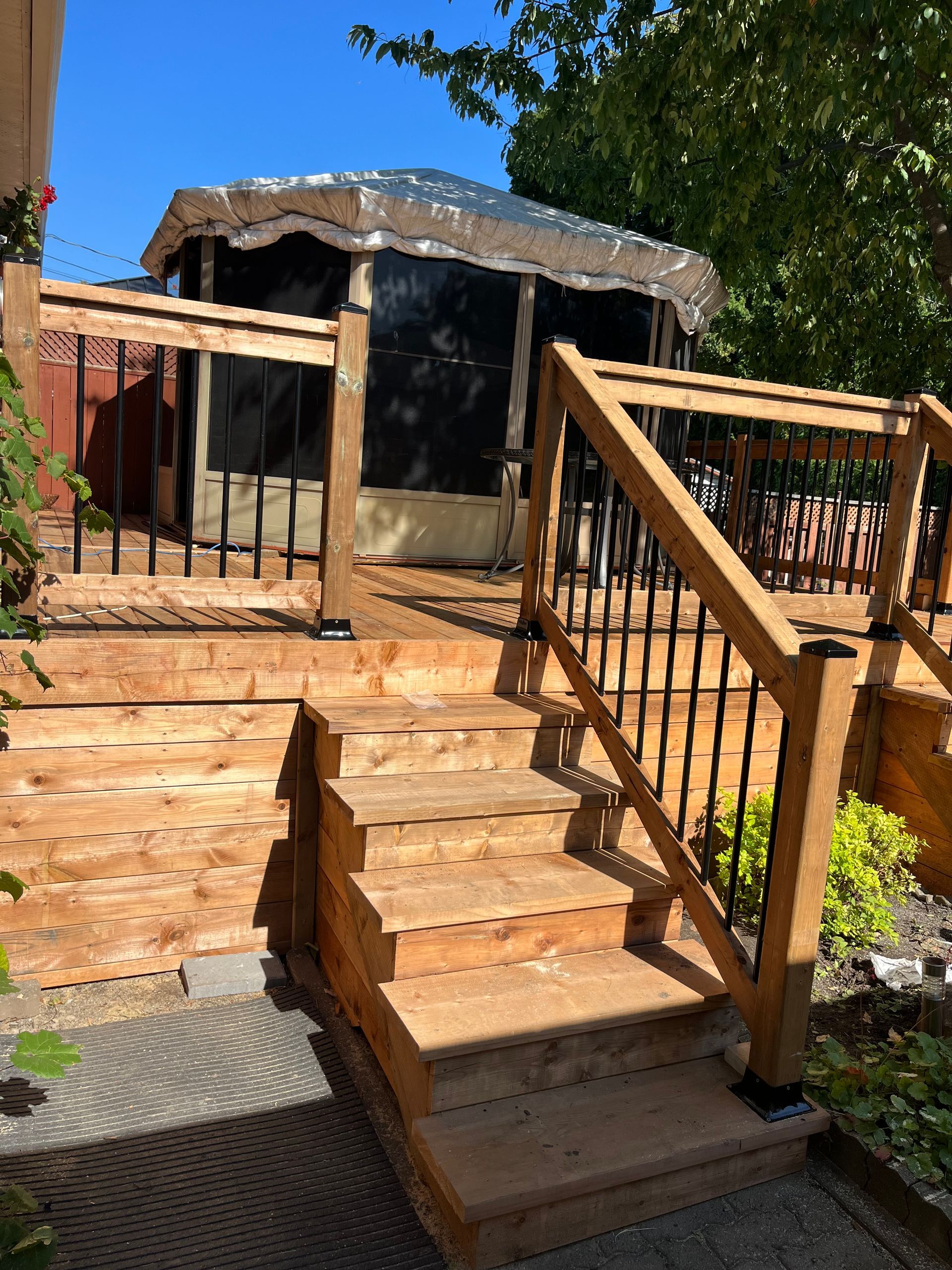 Une terrasse en bois avec des escaliers et un belvédère en arrière-plan