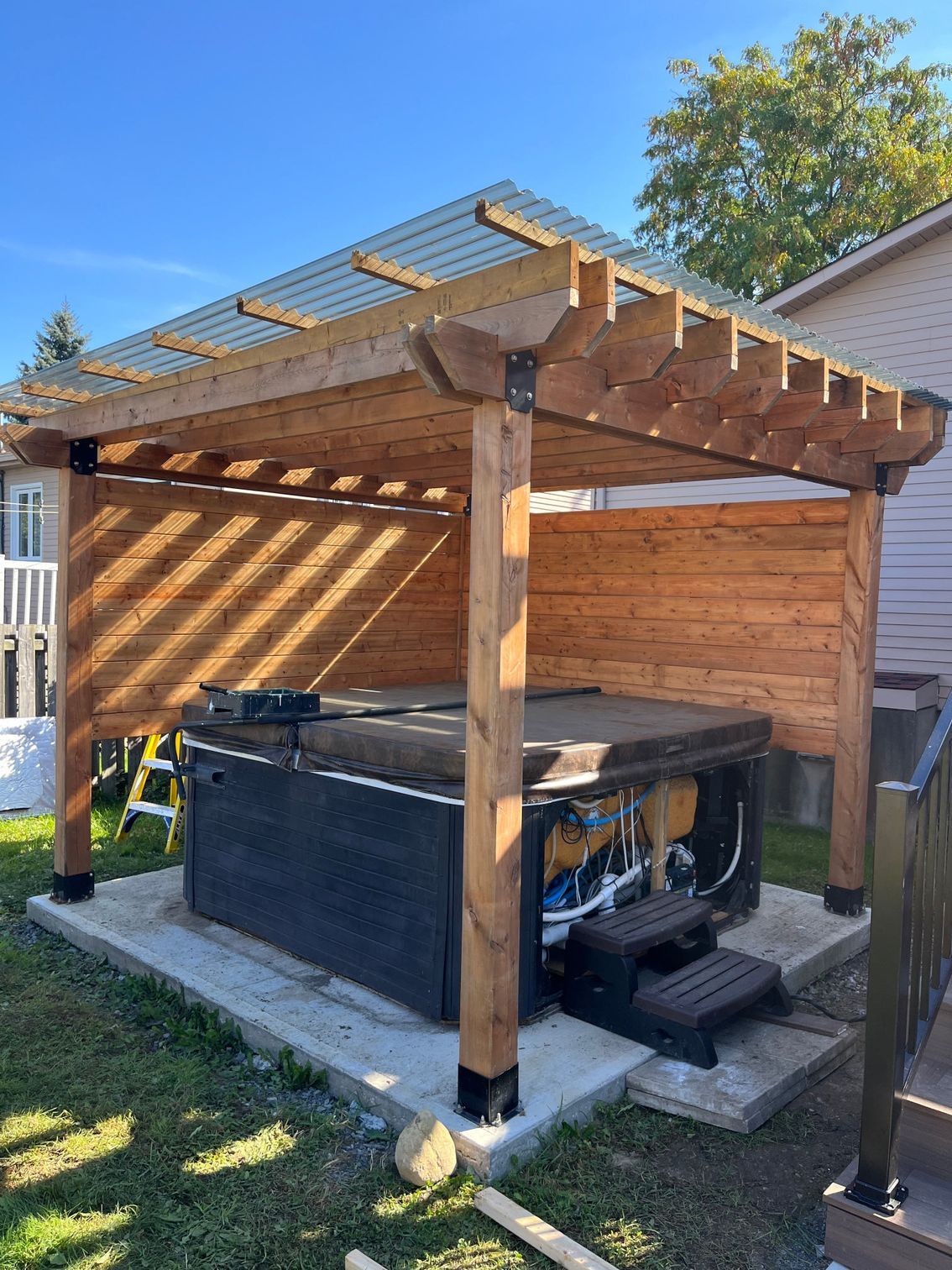 Un bain à remous se trouve sous une pergola en bois dans une cour arrière.