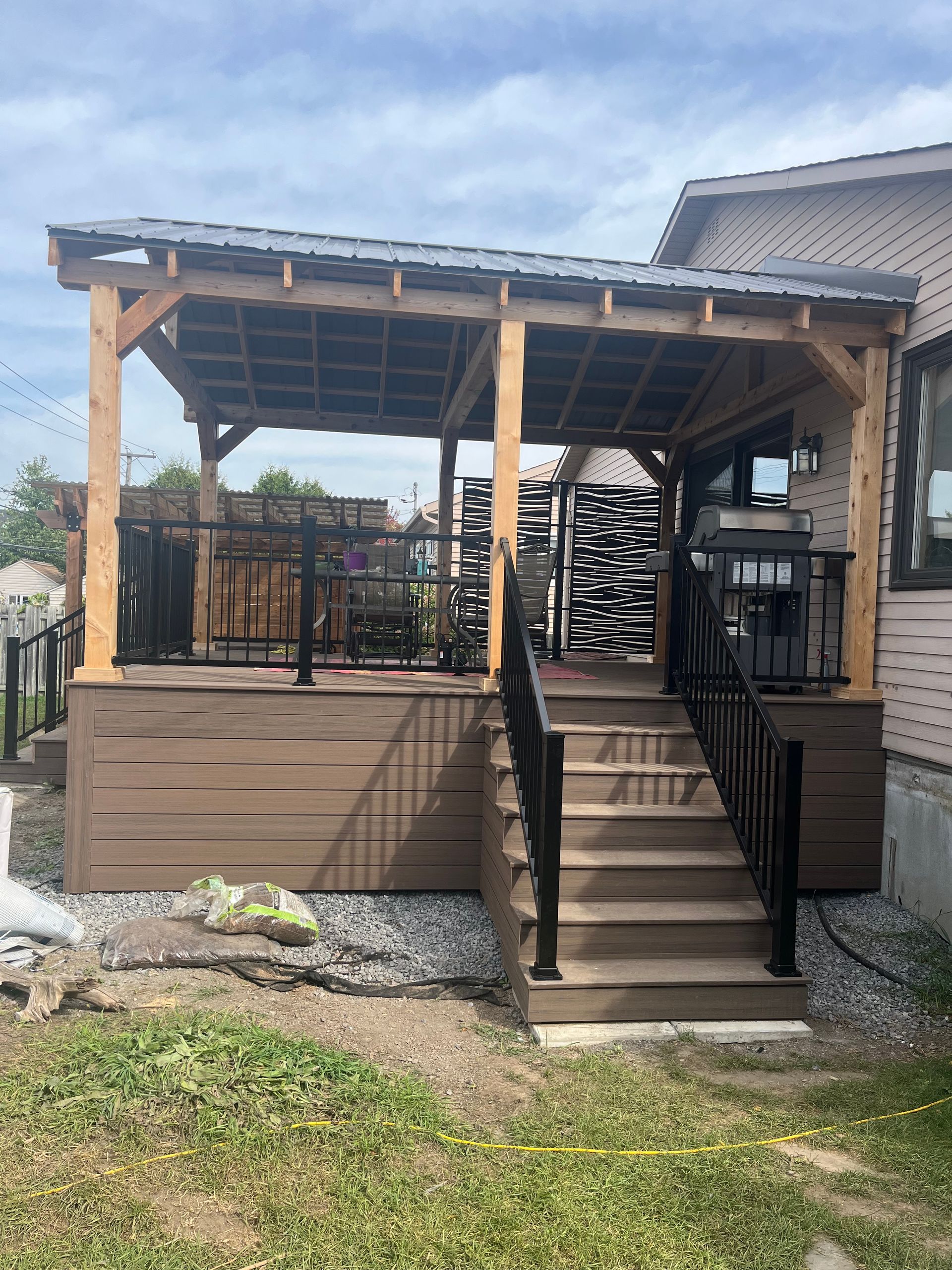Une terrasse en bois avec des escaliers qui y mènent devant une maison.