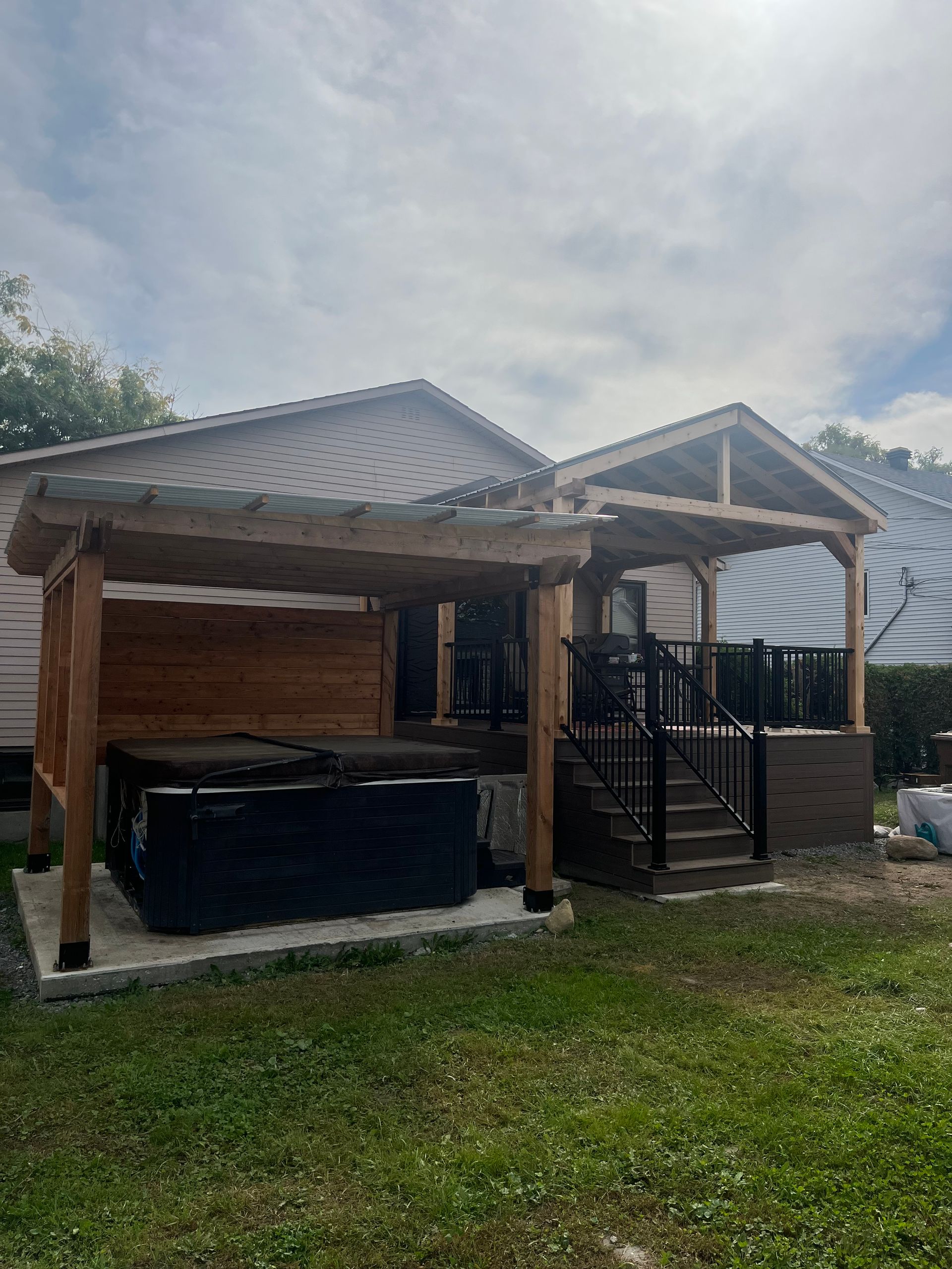 Une maison avec une pergola et un jacuzzi devant.