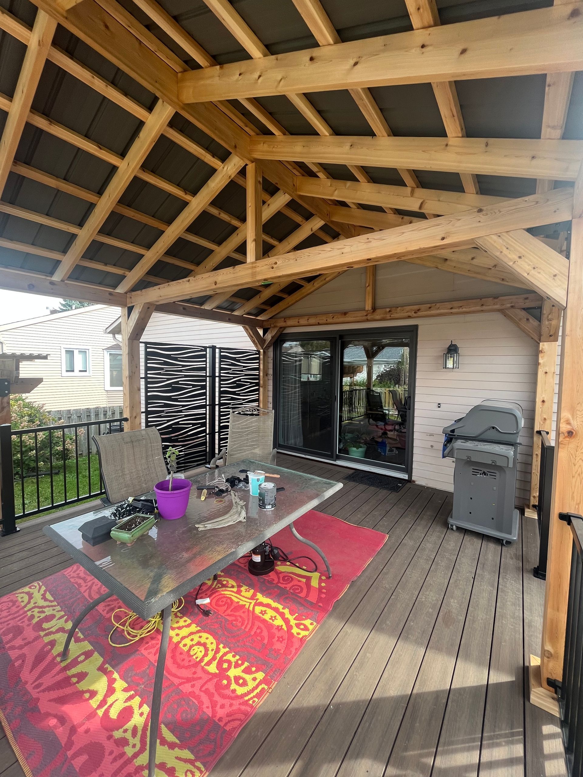 Une terrasse en bois avec une table et des chaises sous un toit en bois.