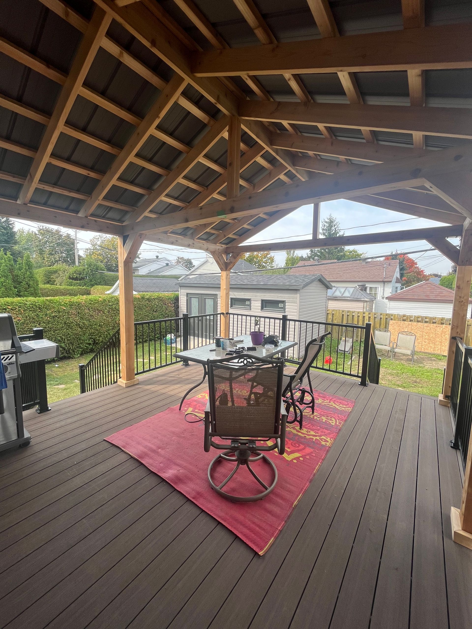 Une terrasse en bois avec une table et des chaises sous un auvent.