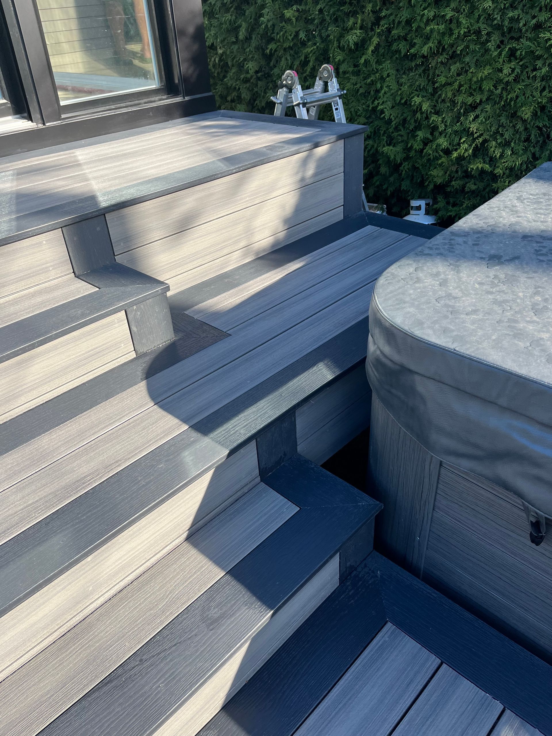 Une terrasse en bois avec des escaliers menant à un bain à remous.