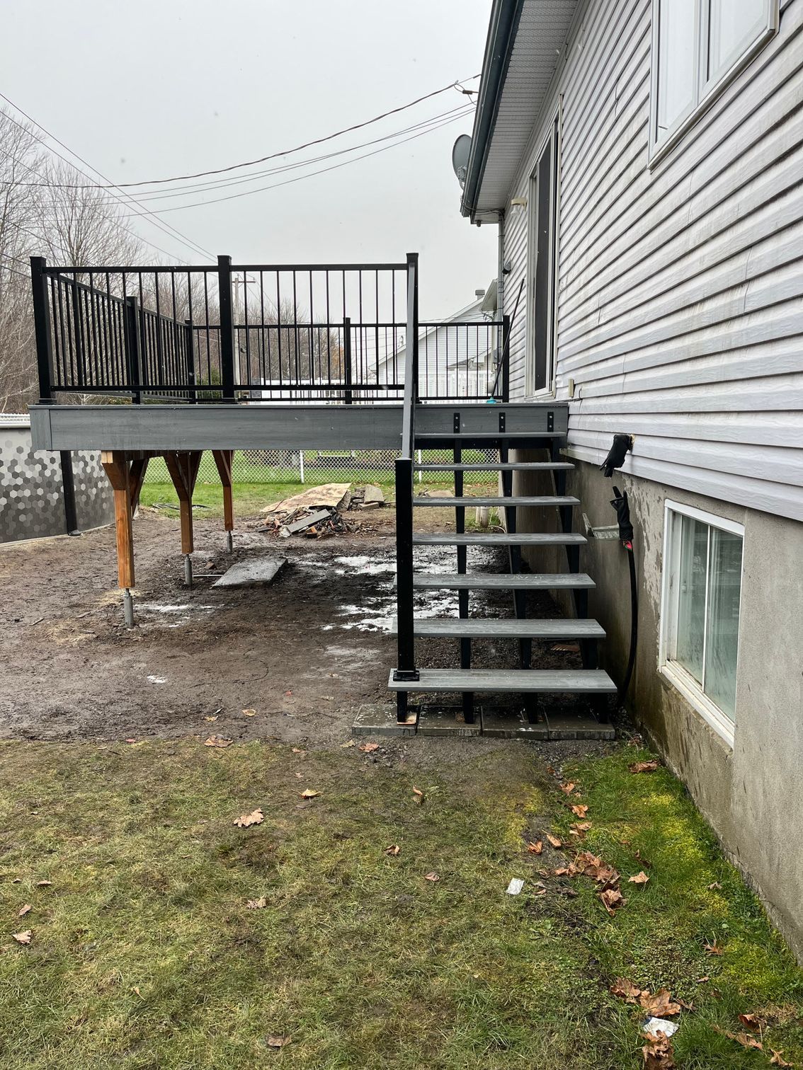 Une terrasse avec des escaliers qui y mènent se trouve dans l'arrière-cour d'une maison.