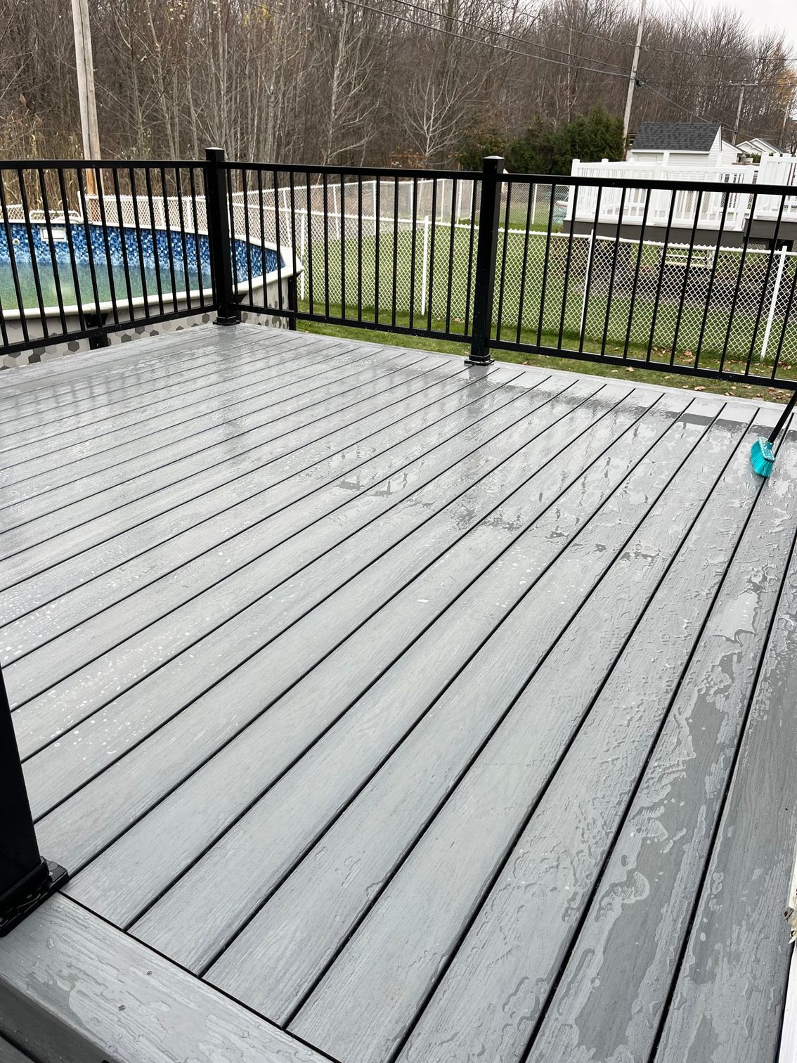 Une terrasse grise avec une balustrade noire et une piscine en arrière-plan.