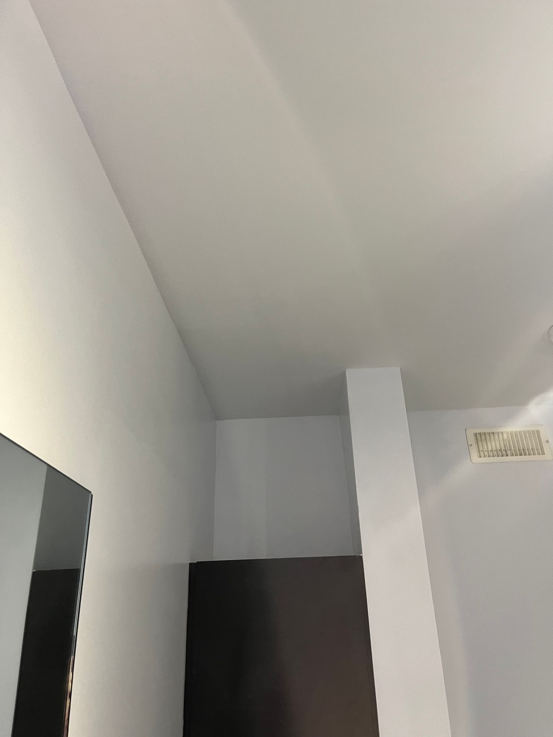 Une pièce avec un plafond blanc et un miroir au mur.