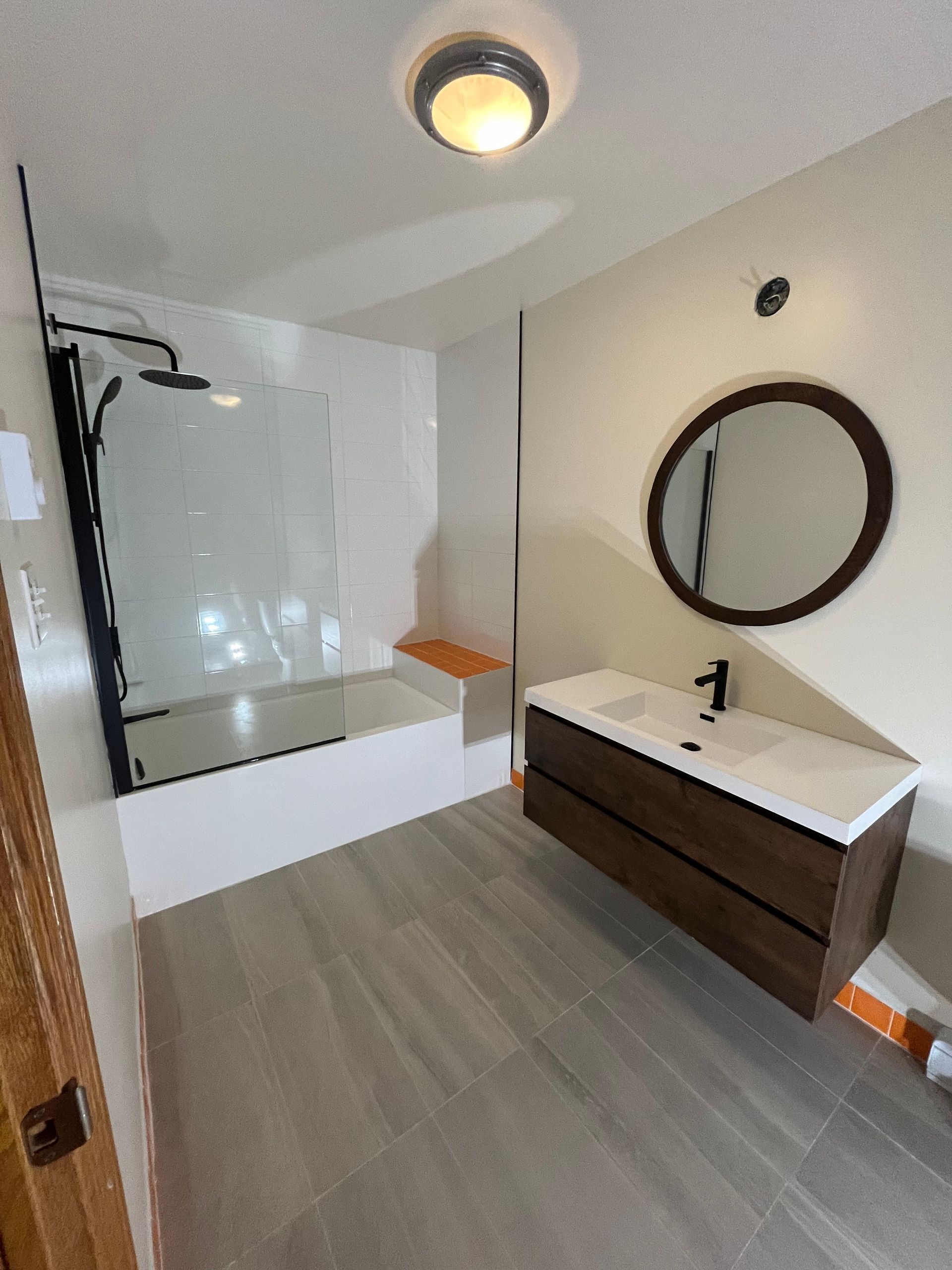 Une salle de bain avec lavabo, baignoire, miroir et douche.