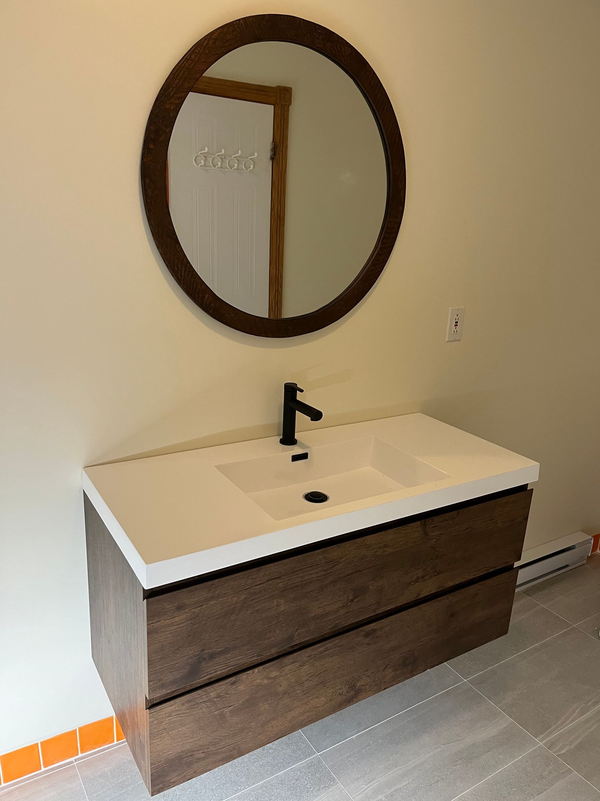 Un lavabo de salle de bain avec un miroir rond au-dessus
